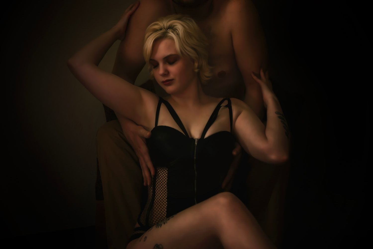 Moody boudoir photoshoot with dramatic lighting and dark background.