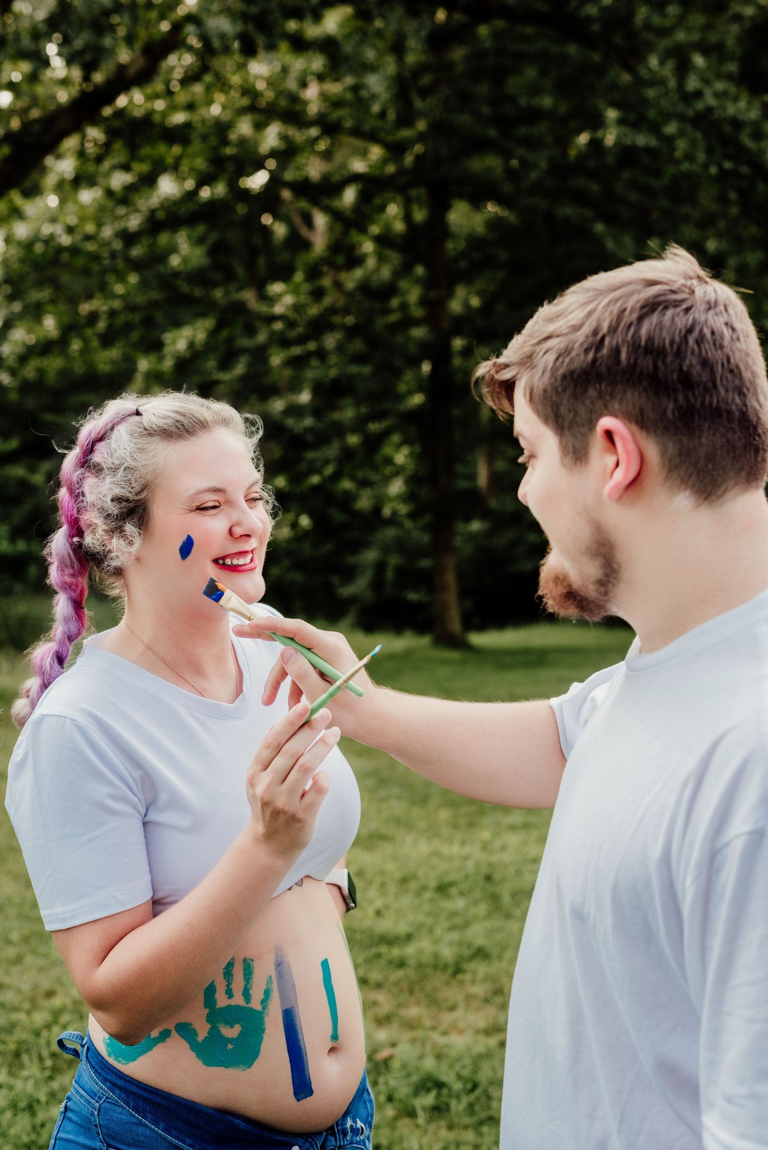 A couple sharing a playful moment while face painting outdoors.