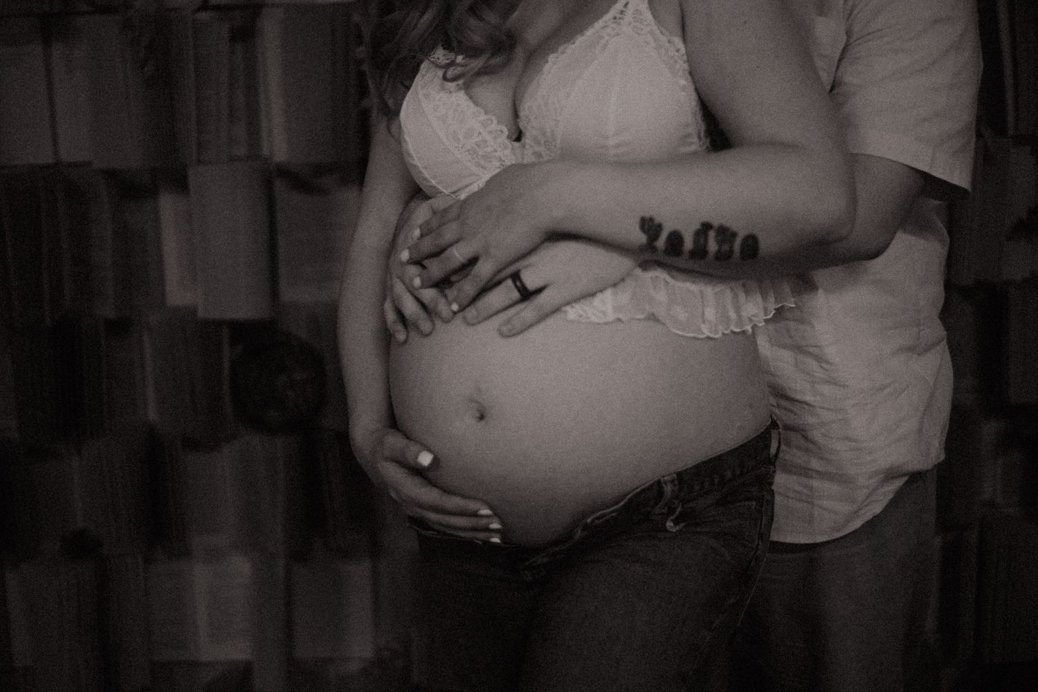 A series of black and white maternity photos showing a pregnant belly in various poses against a dark background.
