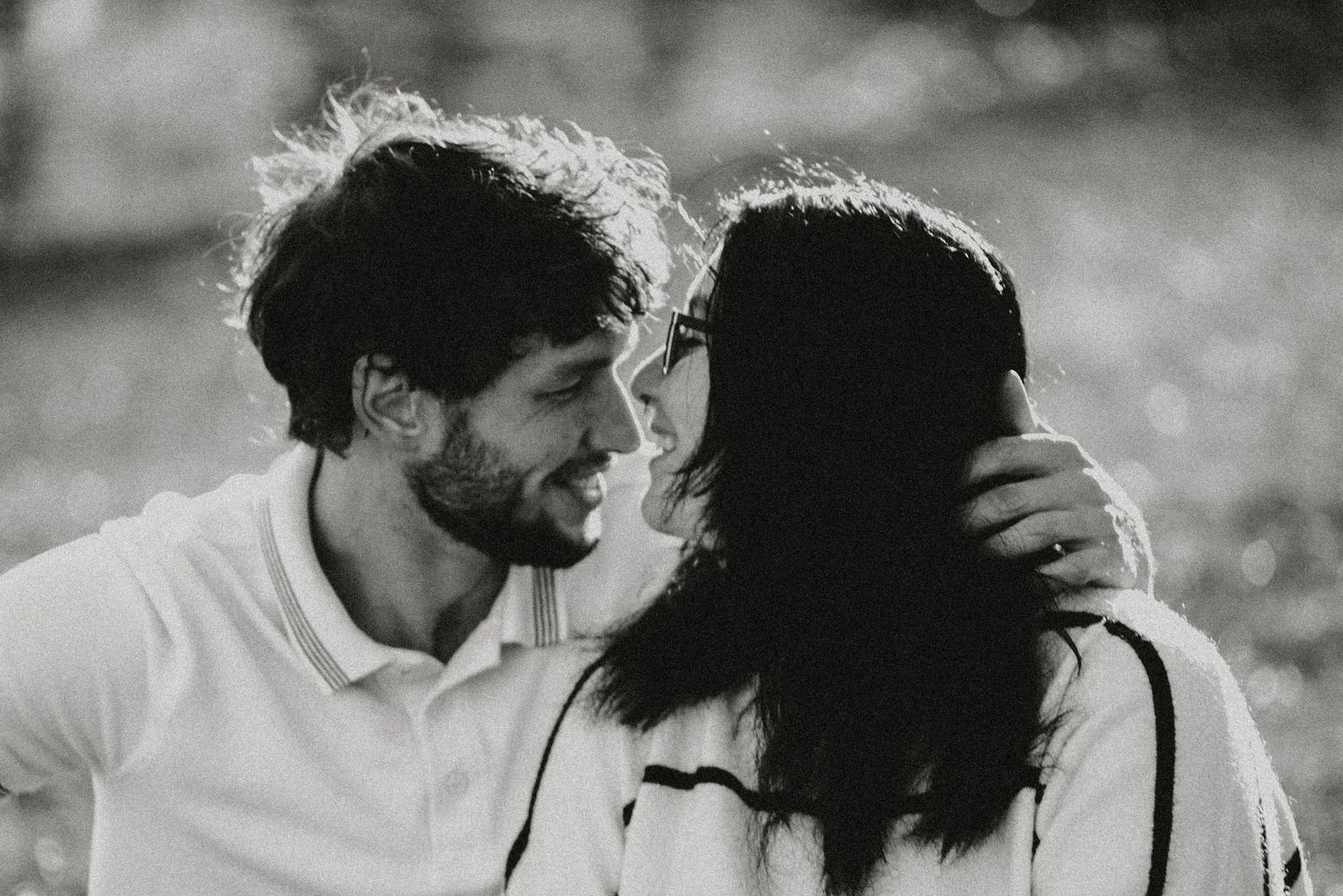 An intimate black and white portrait of a couple sharing a tender moment outdoors.
