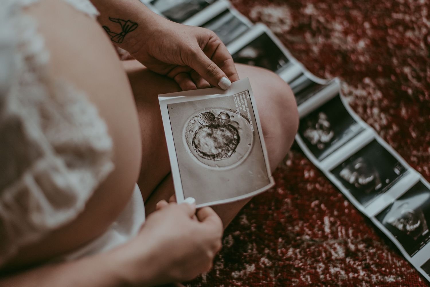 Someone's hands holding and arranging vintage black and white Polaroid photographs on a dark textured surface.