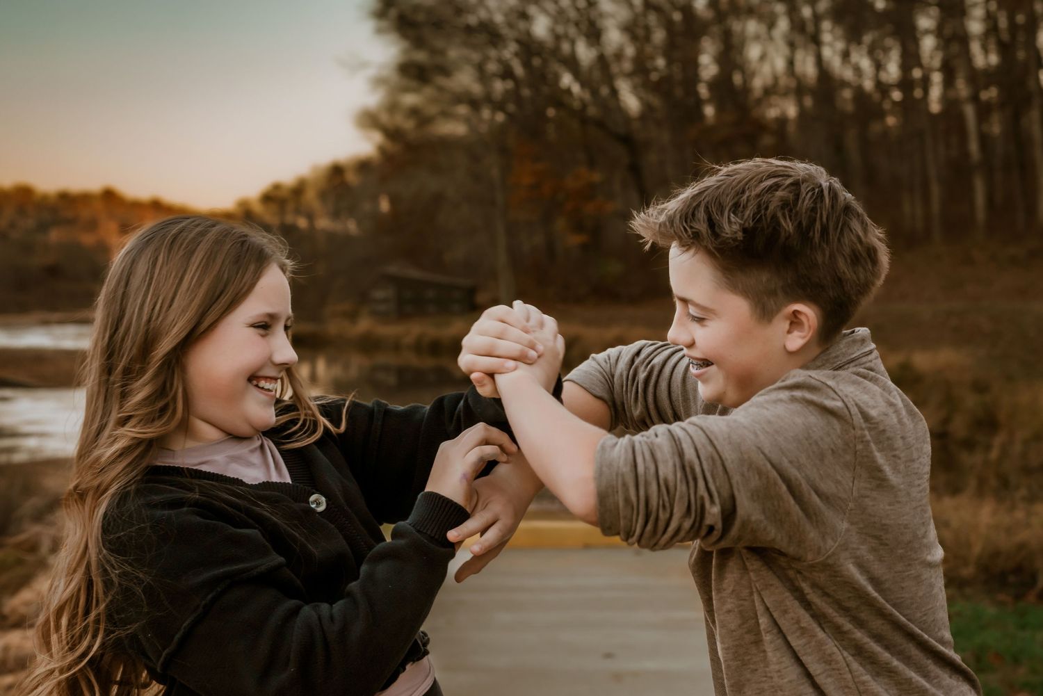 Playful couple dancing together at sunset in autumn setting.