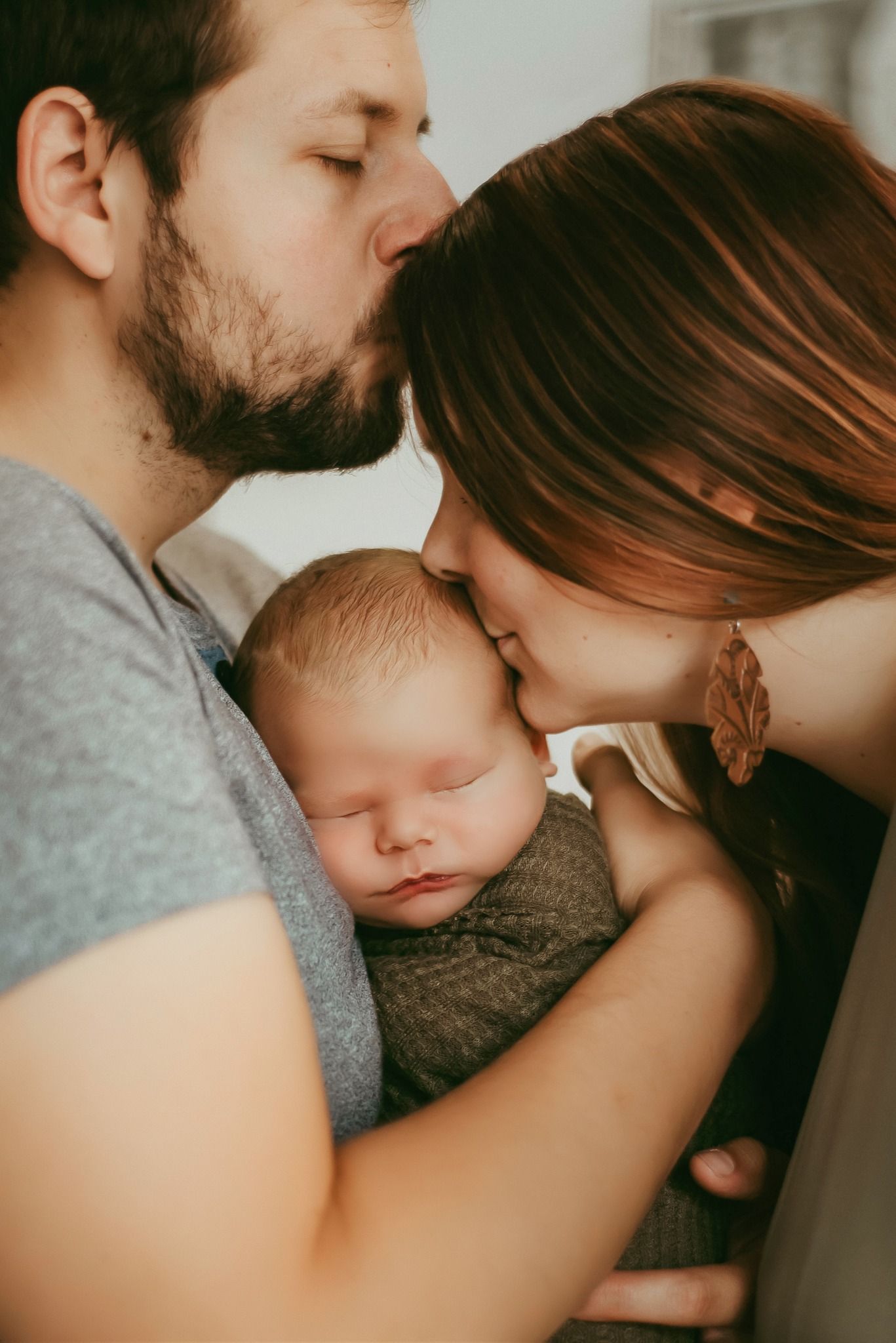 Intimate family portrait with parents tenderly embracing their sleeping baby.