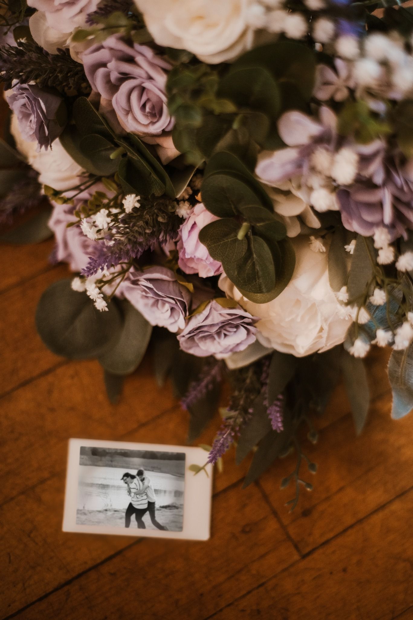 Close-up of pastel rose bouquet with eucalyptus leaves on rustic wooden table.