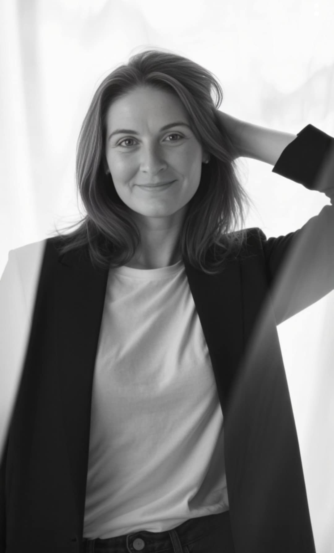 Professional black and white portrait of woman in blazer and white shirt with natural smile.