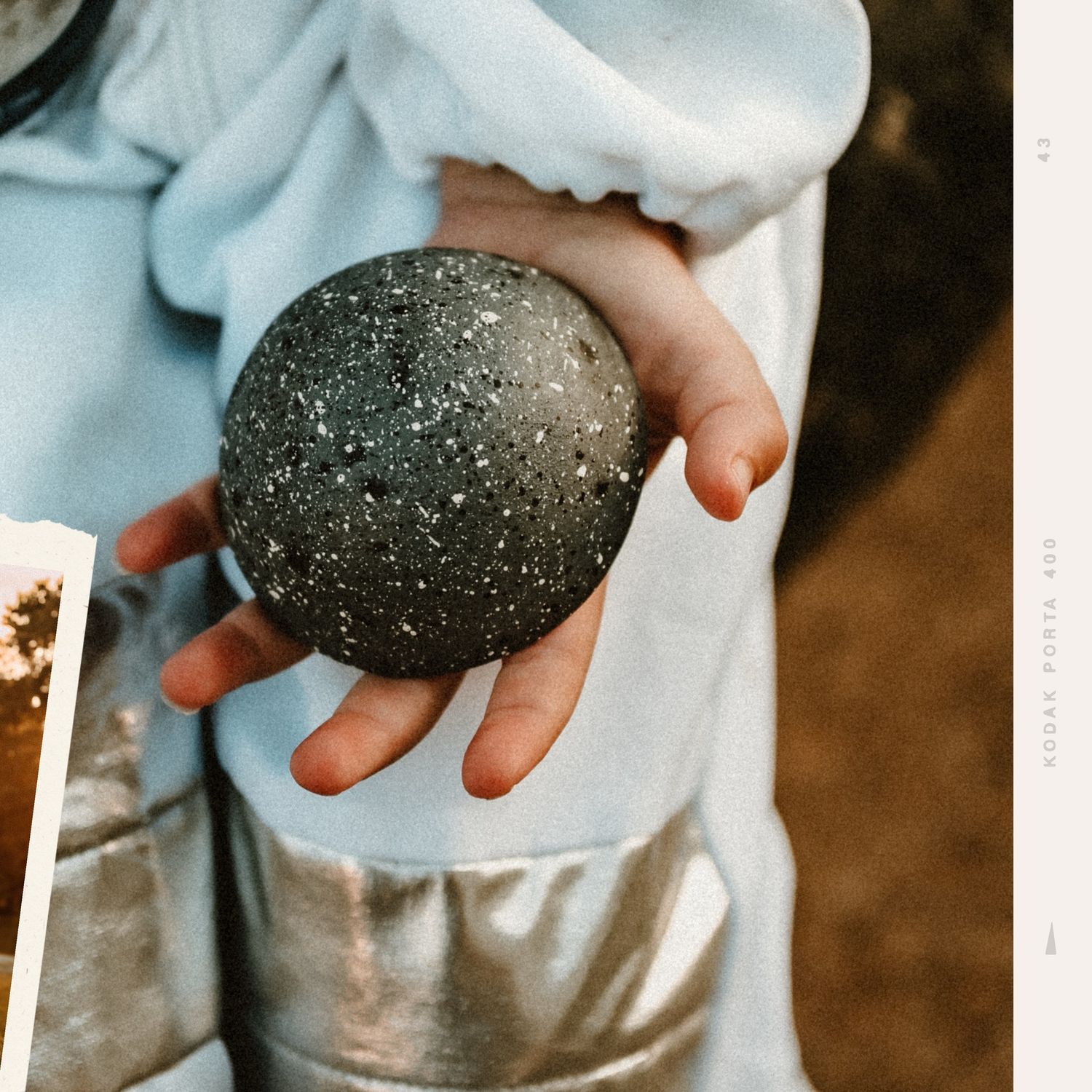 Close-up of small hands holding dark round space-themed props.