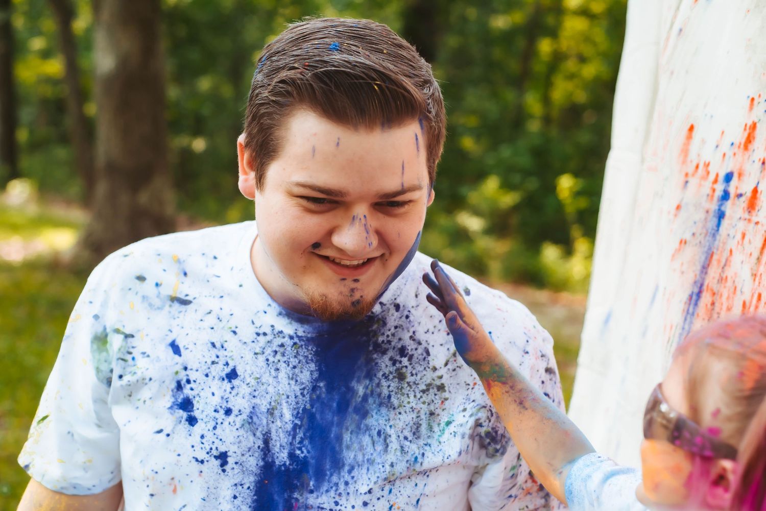Paint splattered portraits showing playful expressions and blue color powder.