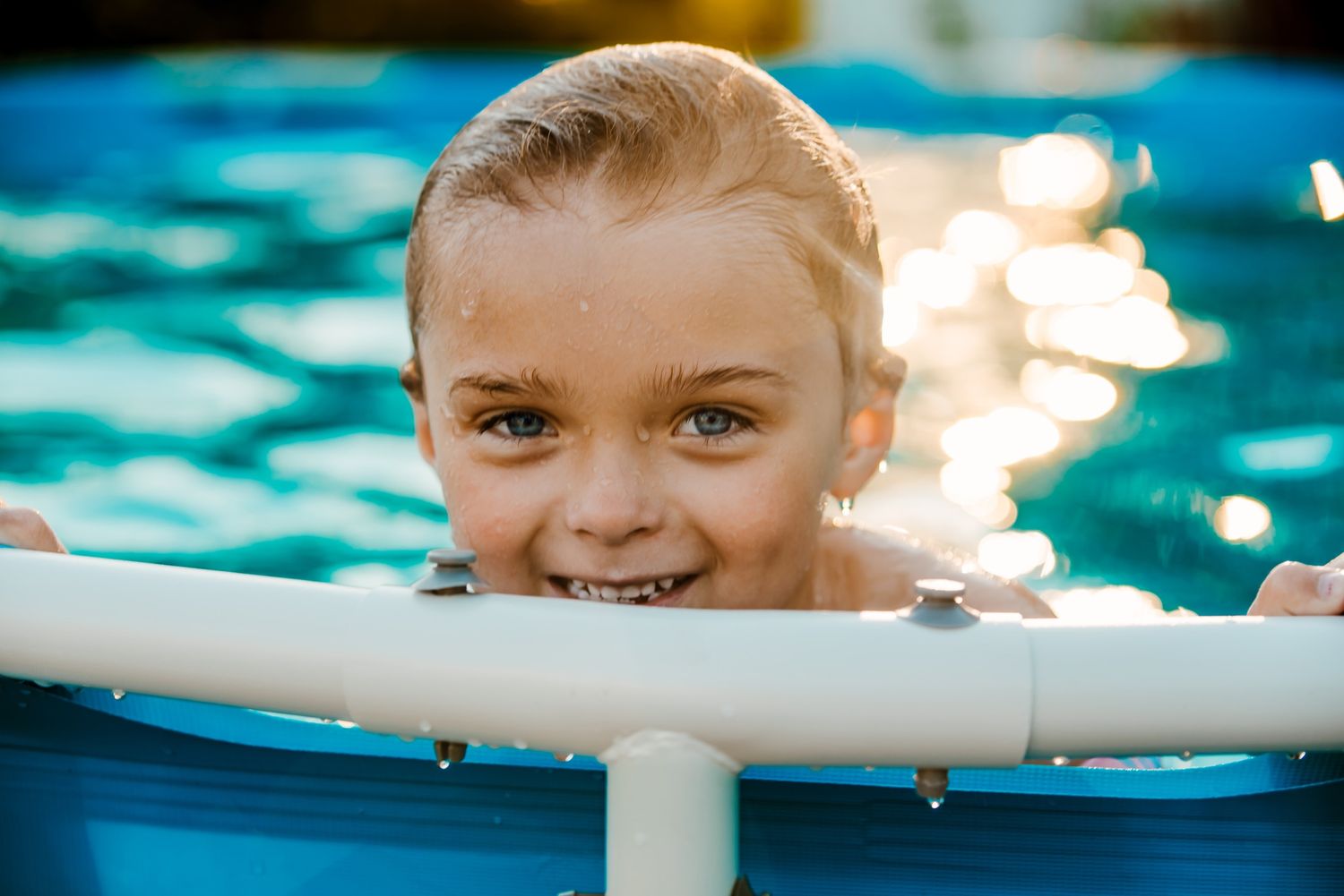 Close-up shot of children swimming and playing in bright blue pool water.