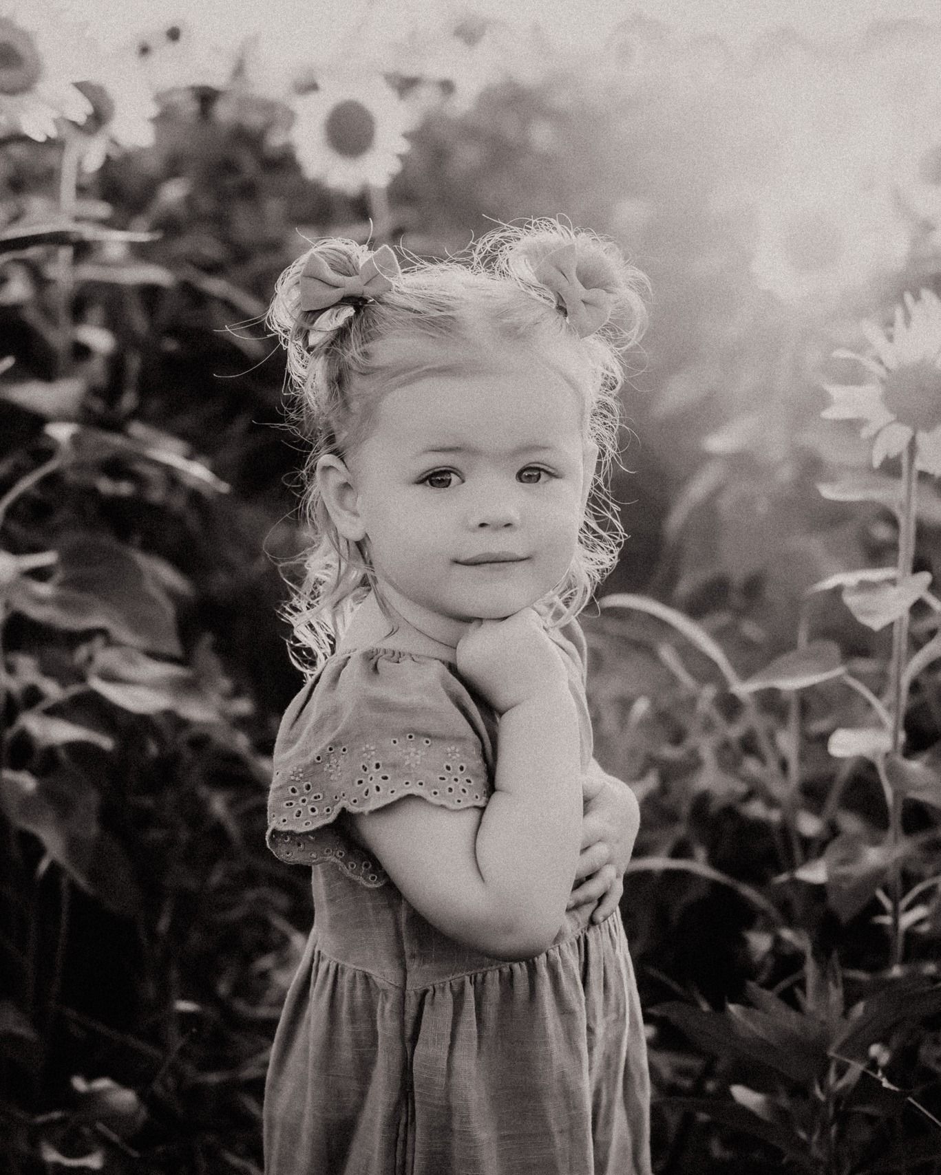 A young child explores a garden setting in a delicate summer dress.