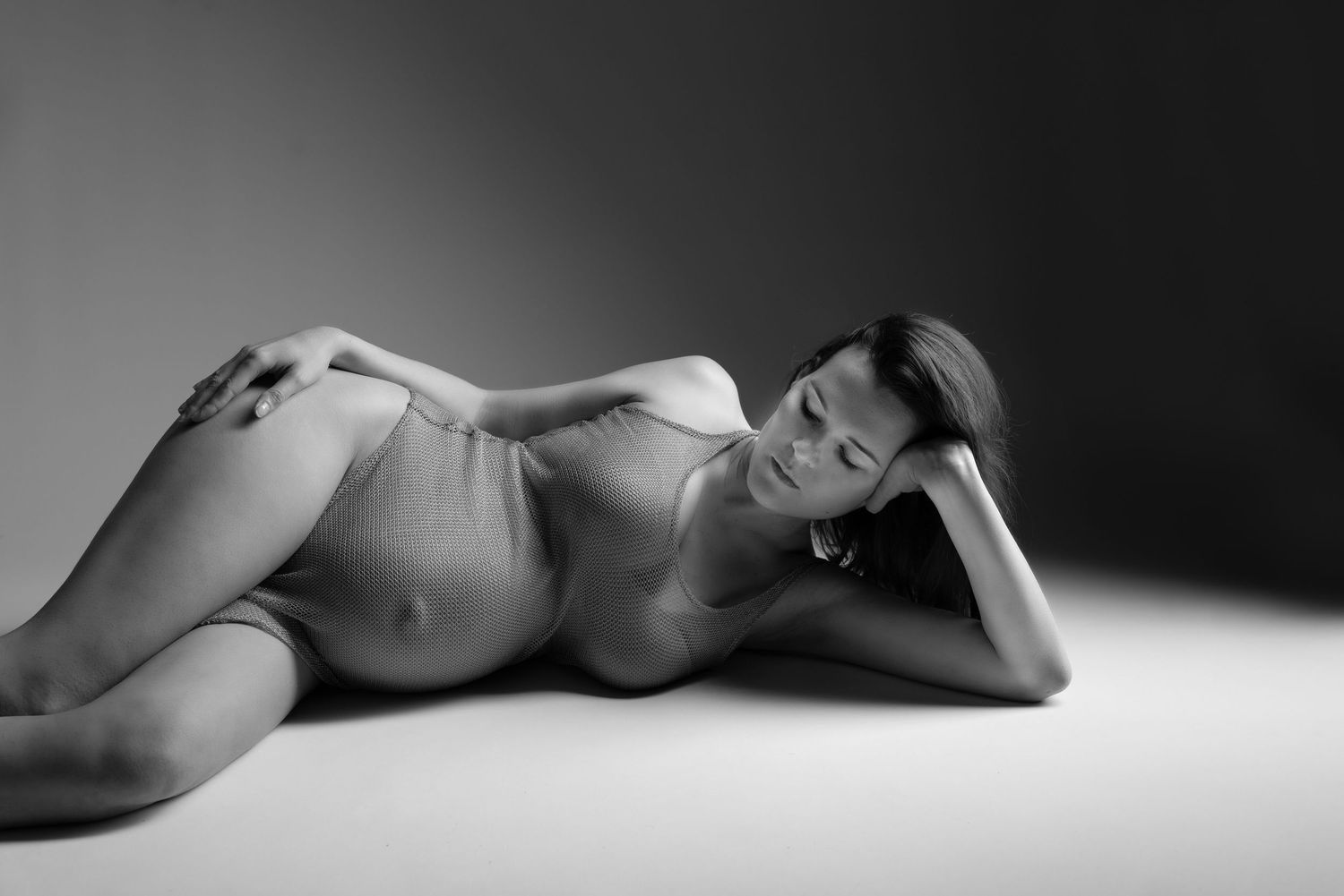 séance photo grossesse en noir et blanc, femme enceinte allongée en studio dans le Jura