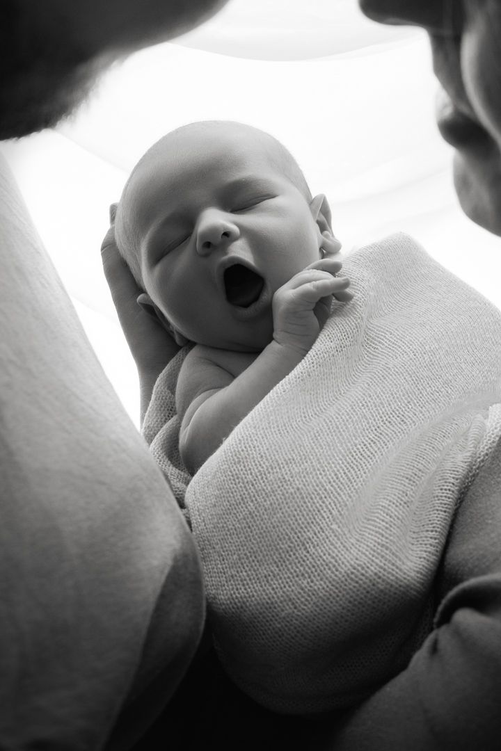 bébé endormi dans les bras séance naissance studio Jura