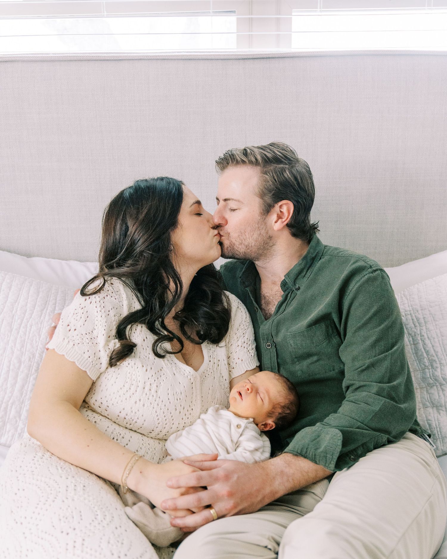 A couple shares tender moments while resting together on white bedding in a series of intimate photographs.
