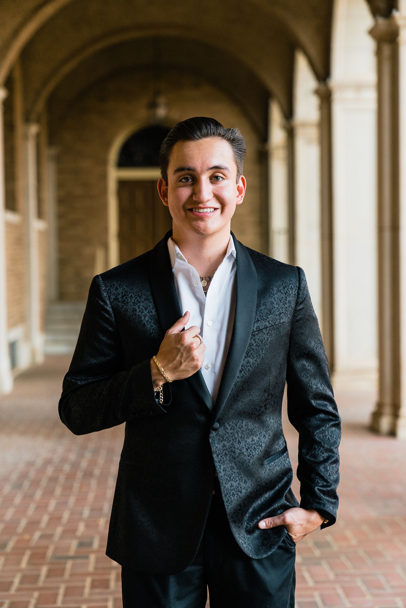 Professional wearing dark suit jacket poses playfully in four sequential shots along brick corridor with arches.