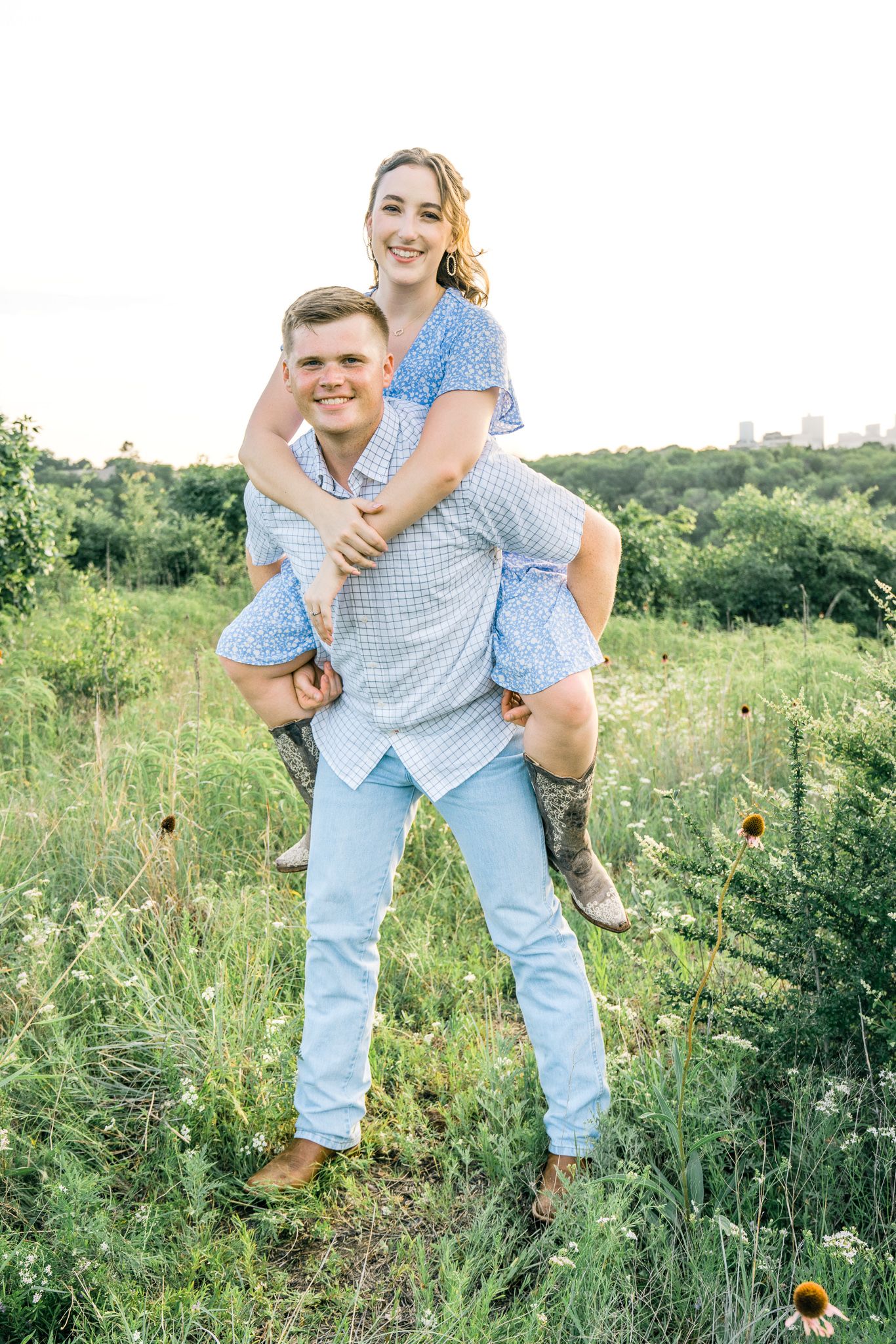 A playful piggyback ride in a summer meadow with light blue coordinated outfits.