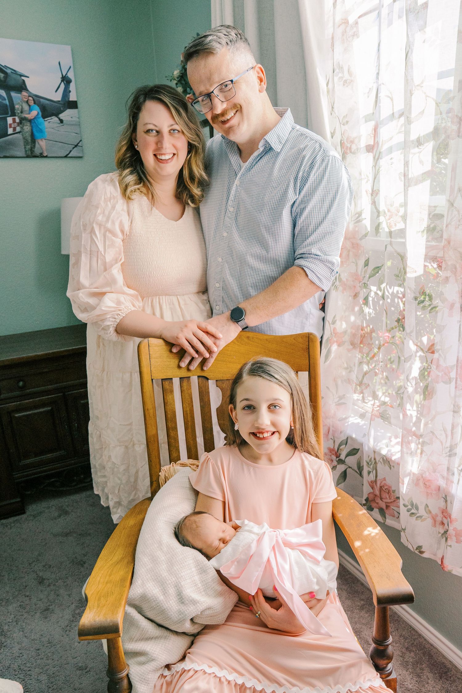 A family portrait in soft natural light with mint green walls and delicate floral curtains.