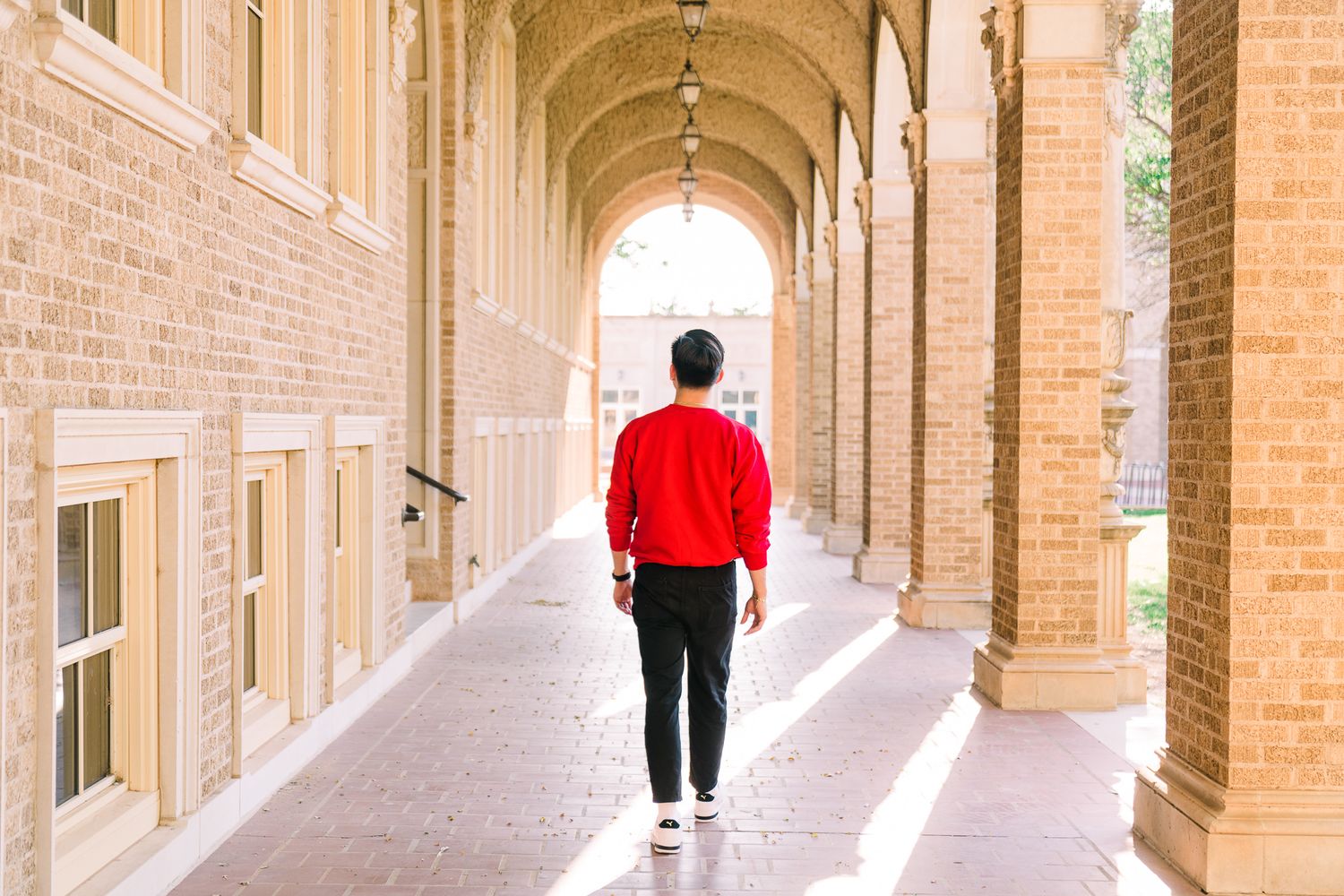 Long arched brick hallway with columns and windows in a historic university building.
