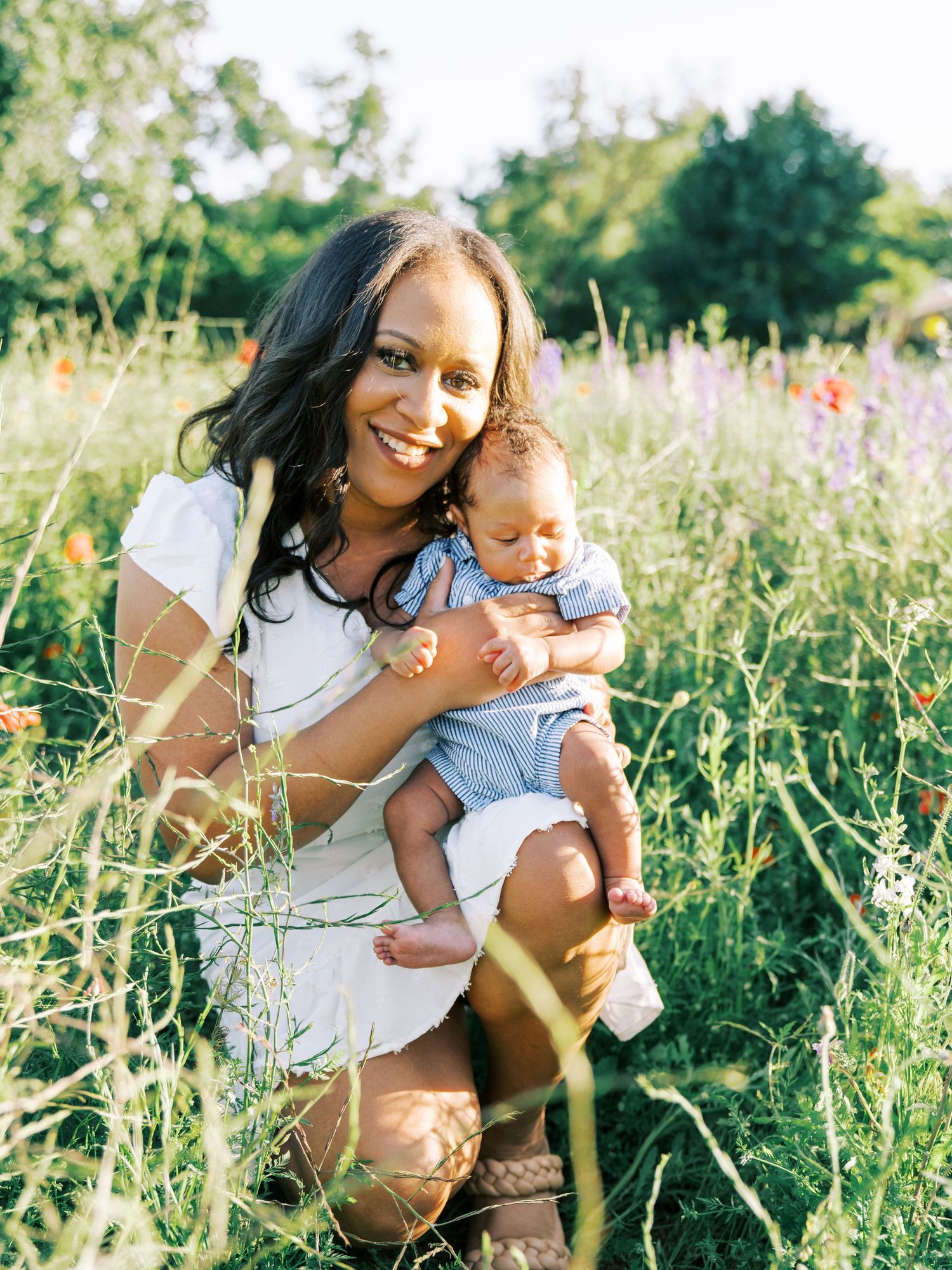 Two people share joyful moments together in a sunlit wildflower meadow during a summer photoshoot.