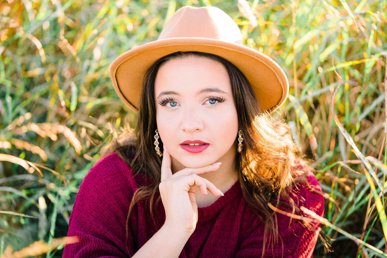 A series of outdoor portrait shots showing different poses in autumn foliage with a burgundy sweater and tan hat.