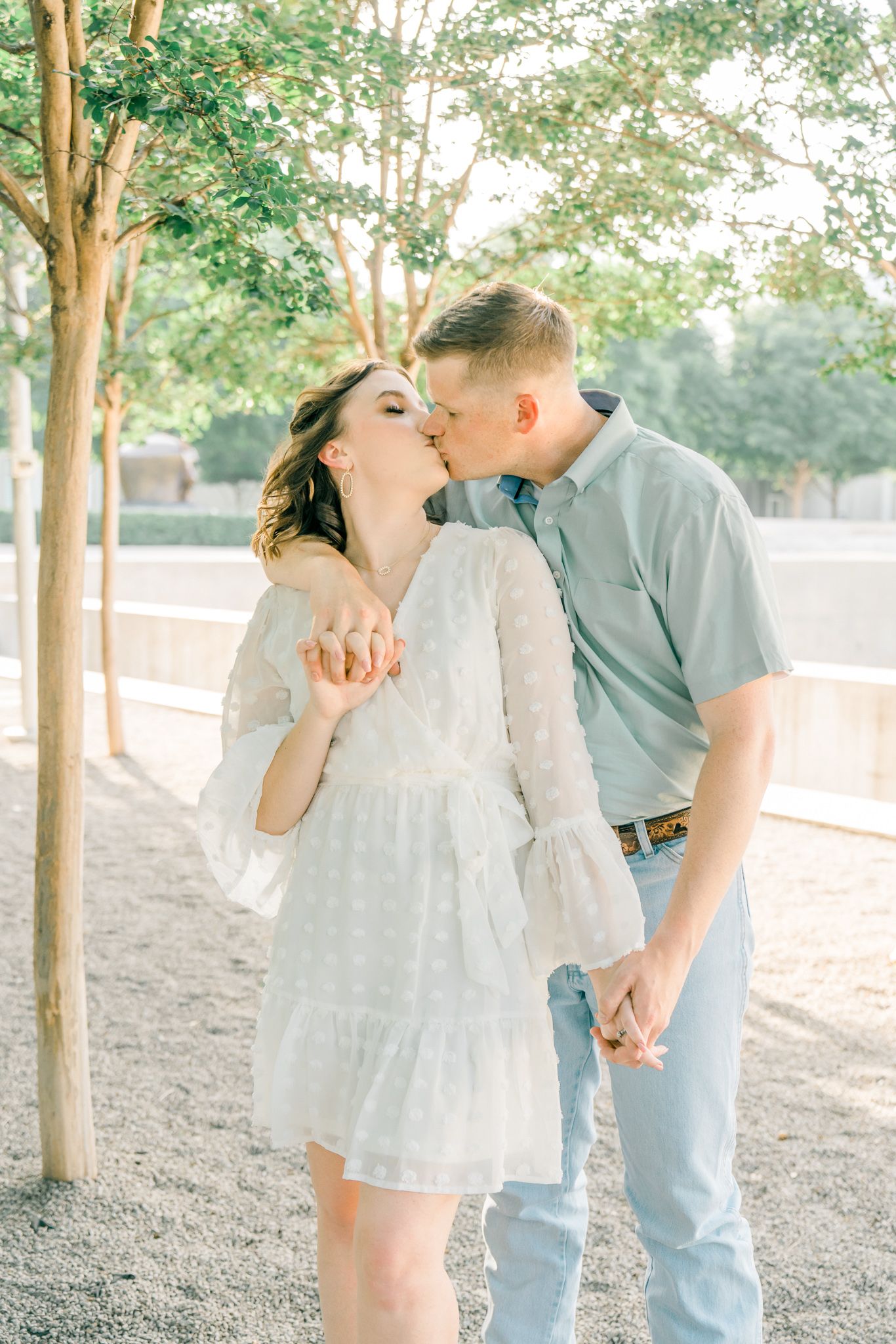 Romantic couple sharing tender moments during golden hour photoshoot in park setting.