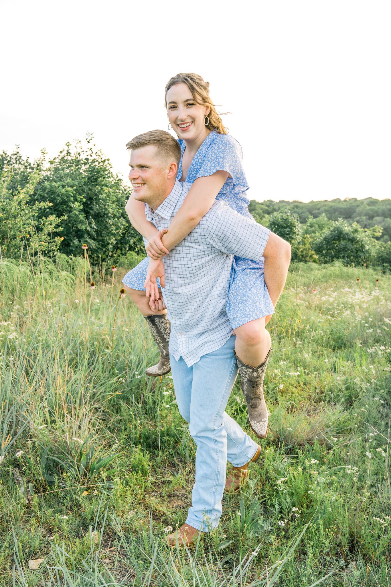 A joyful piggyback moment captured in a green meadow with natural wildflowers.