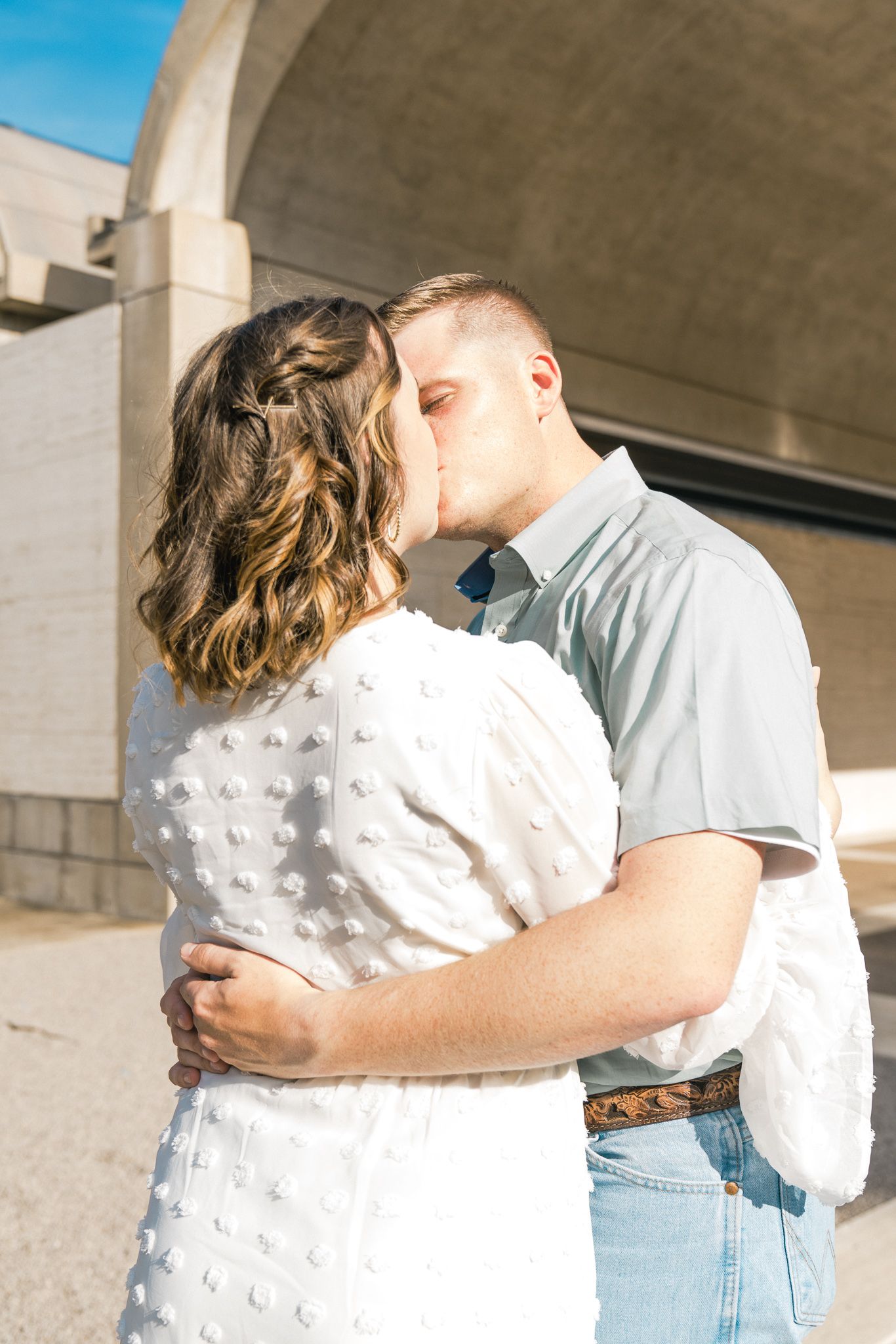 A couple in casual attire embracing against a concrete wall background in a series of romantic poses.