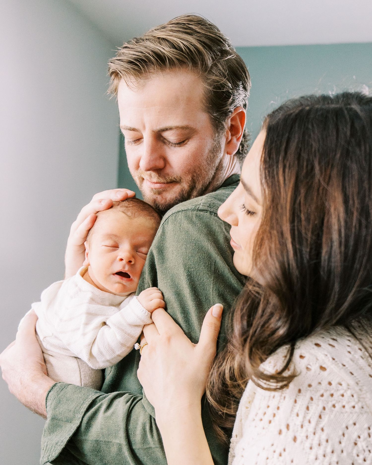 Parents holding and comforting their sleeping newborn baby in a tender family moment.