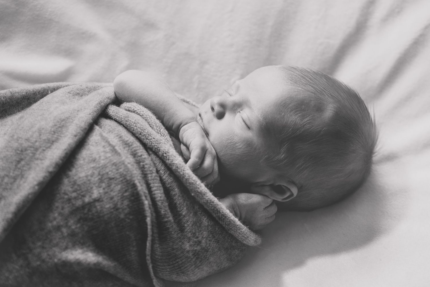 A series of black and white photographs showing a sleeping baby in different positions.