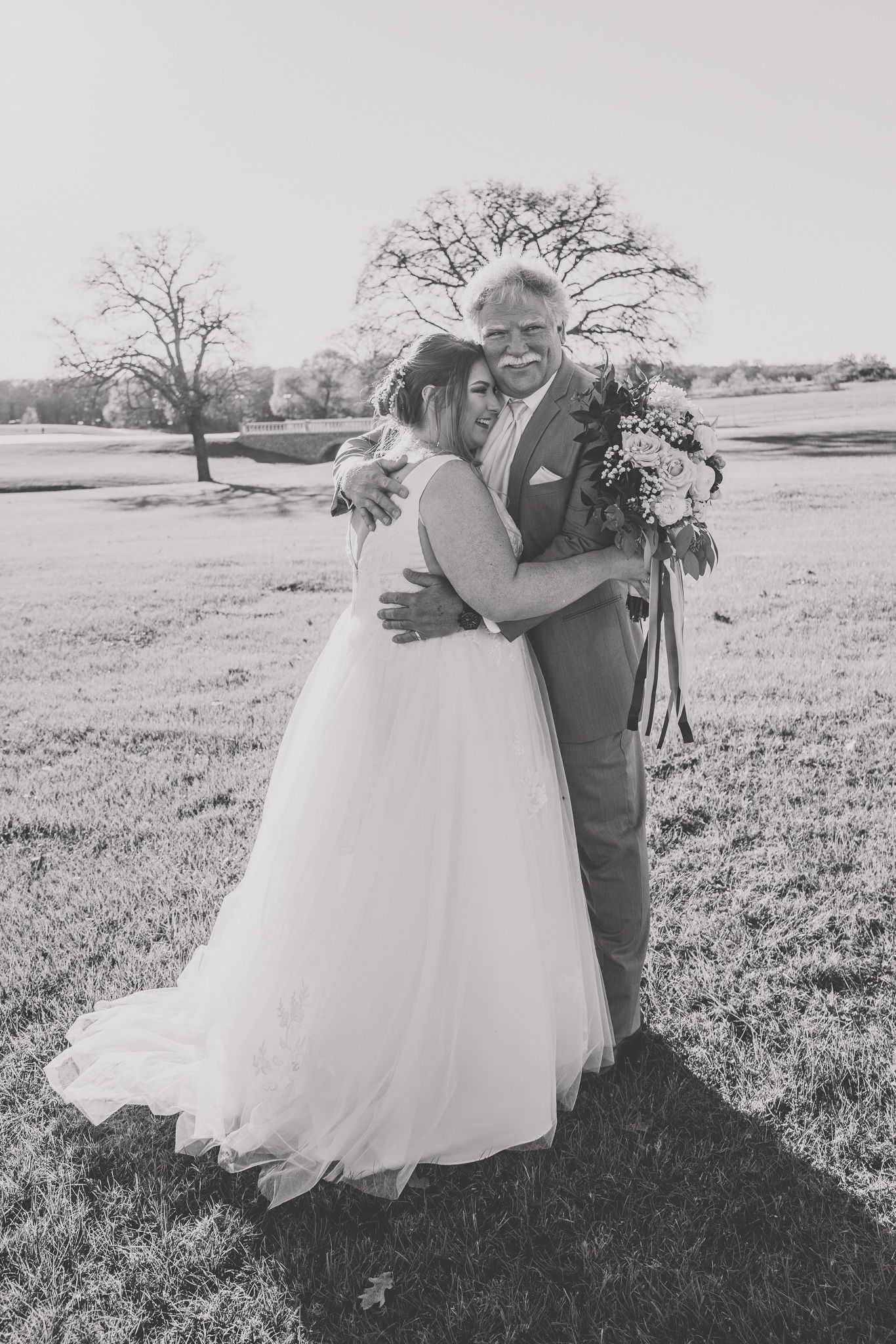 Black and white wedding portraits captured in an open field with dramatic composition.