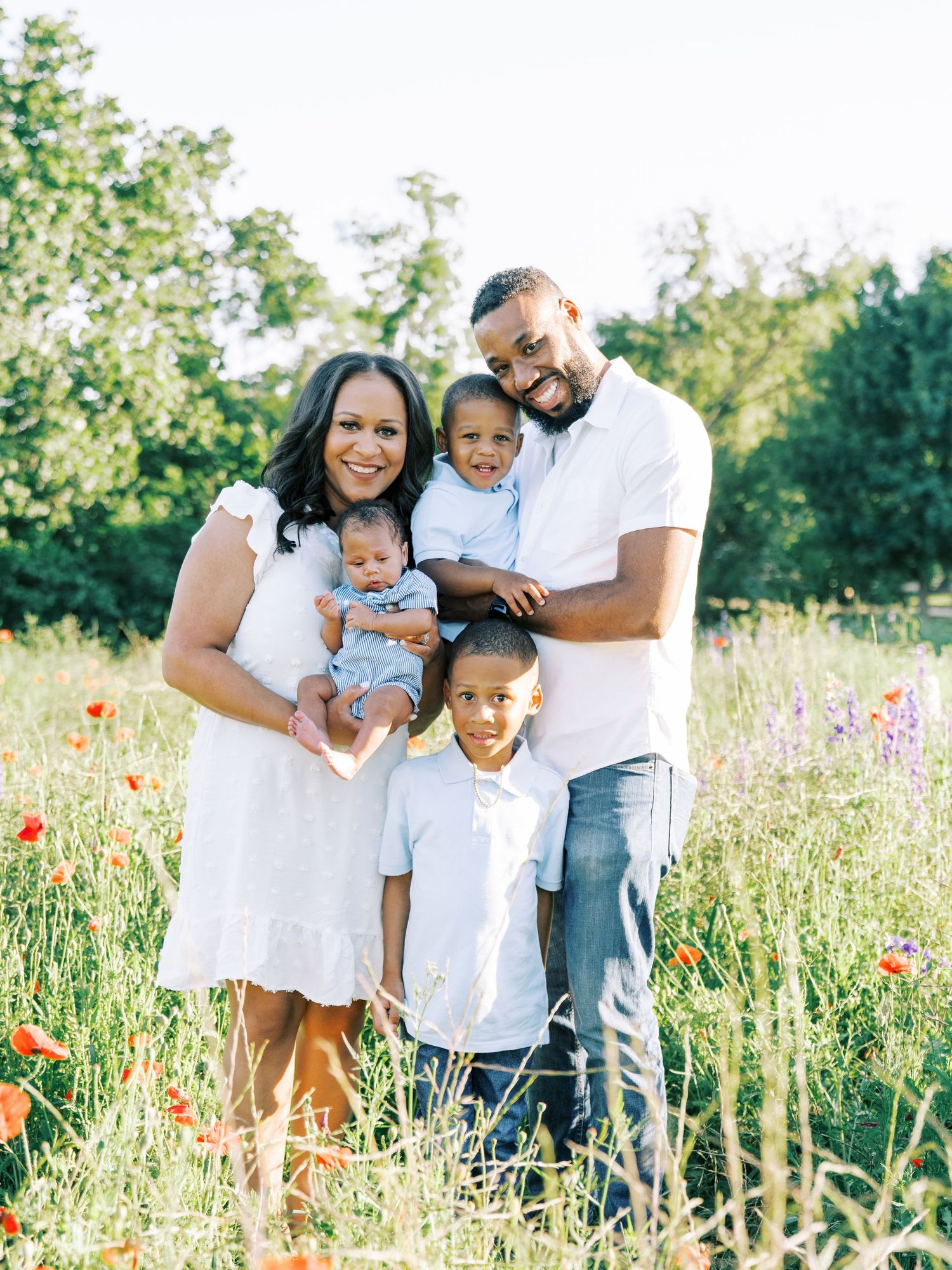 A family poses together in a field of colorful wildflowers during a summer photoshoot.