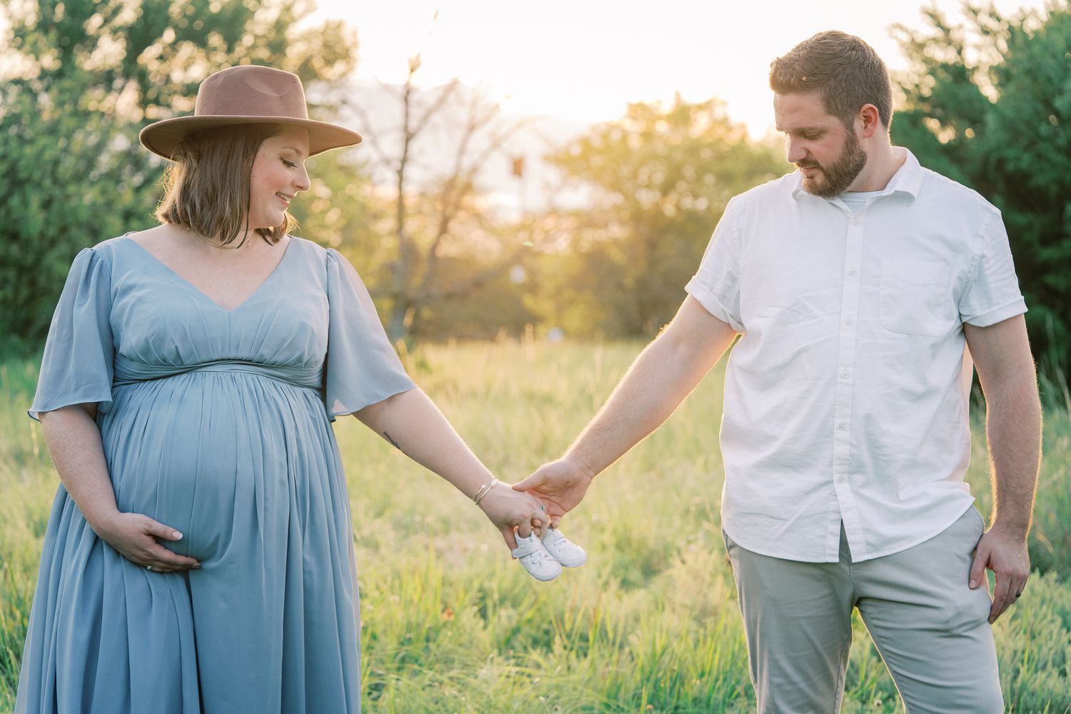 Candid maternity photography showing tender moments between couple in outdoor garden setting.