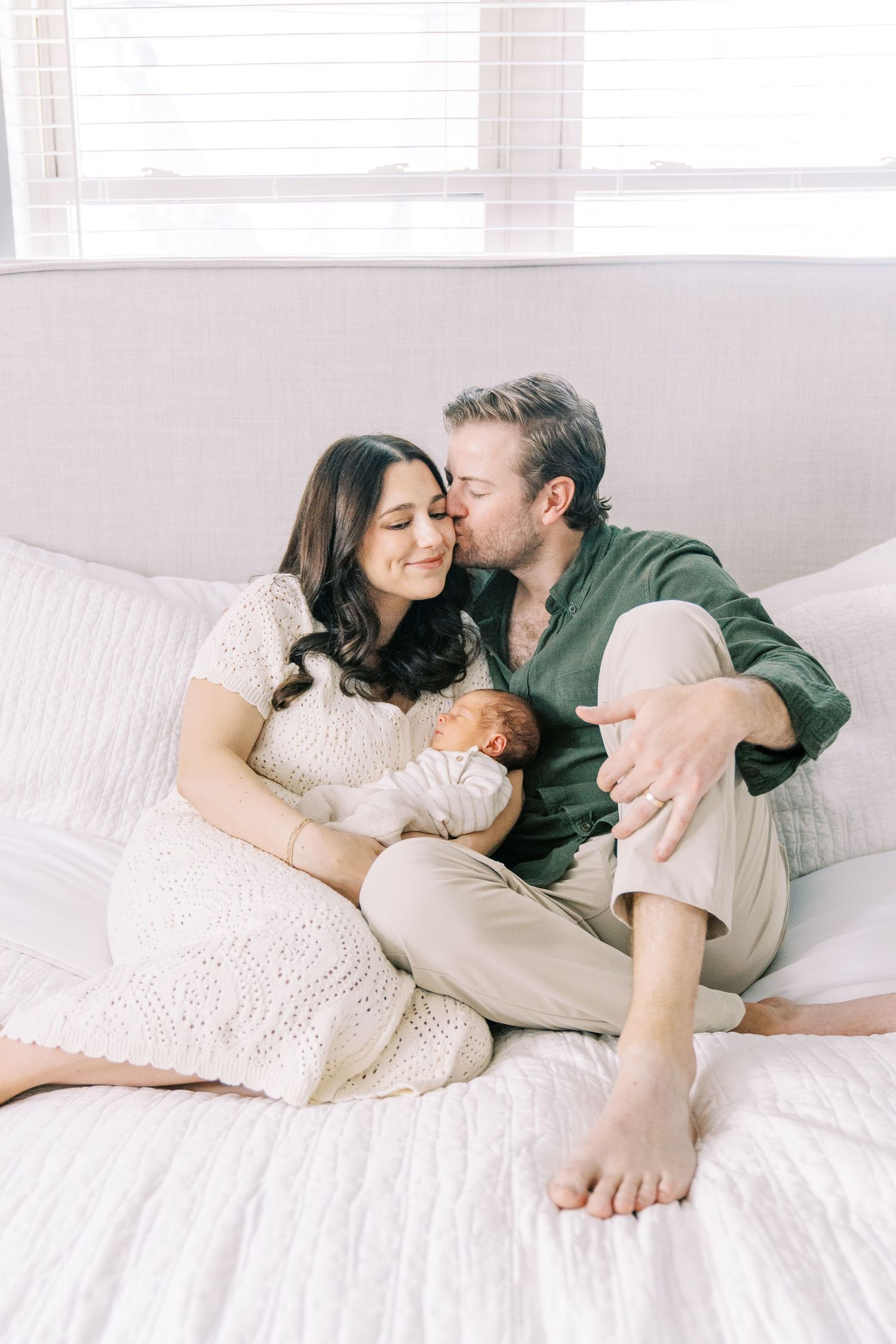 Intimate couple in white lying together on bed sharing tender moments in romantic lifestyle photoshoot.