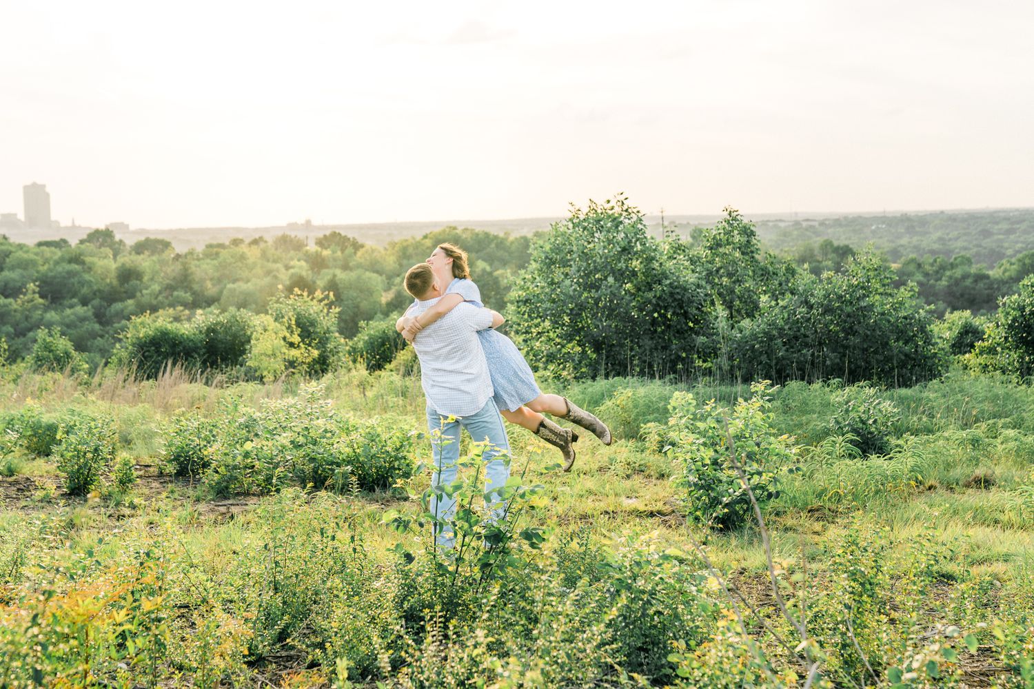 Natural meadow setting with green vegetation and scattered wildflowers under a bright sky.