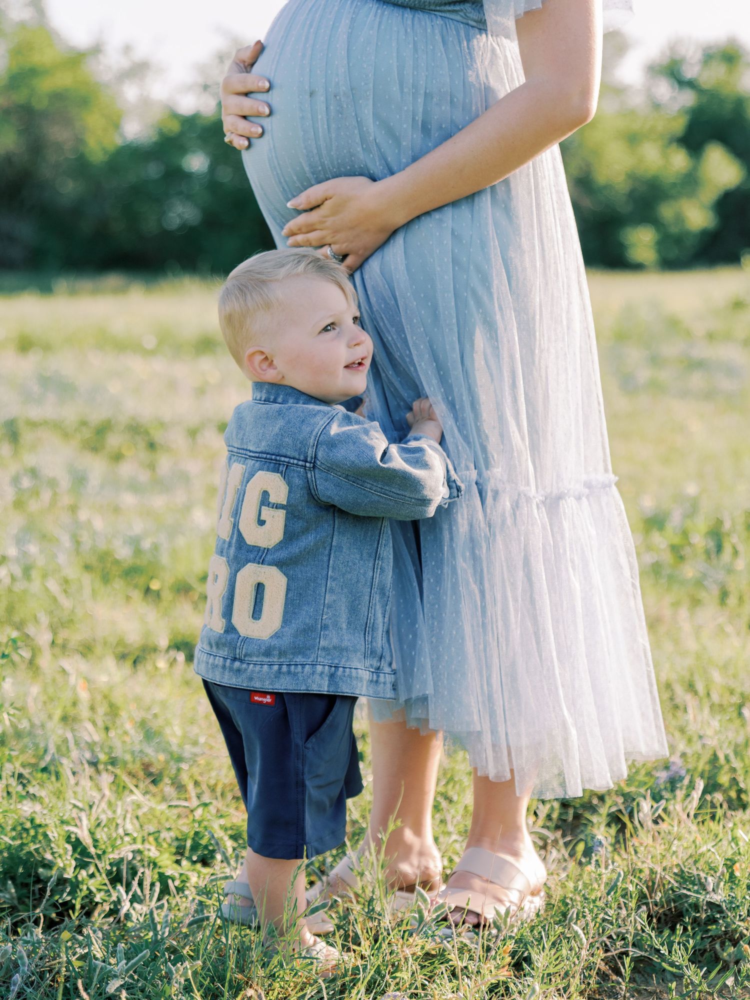 Sweet candid interactions between family members in a grassy field during sunset.