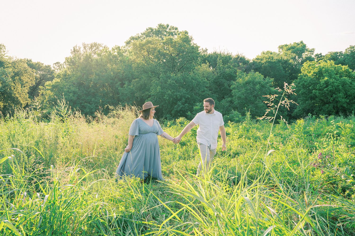 A romantic outdoor photoshoot in tall grass and wildflowers during golden hour.