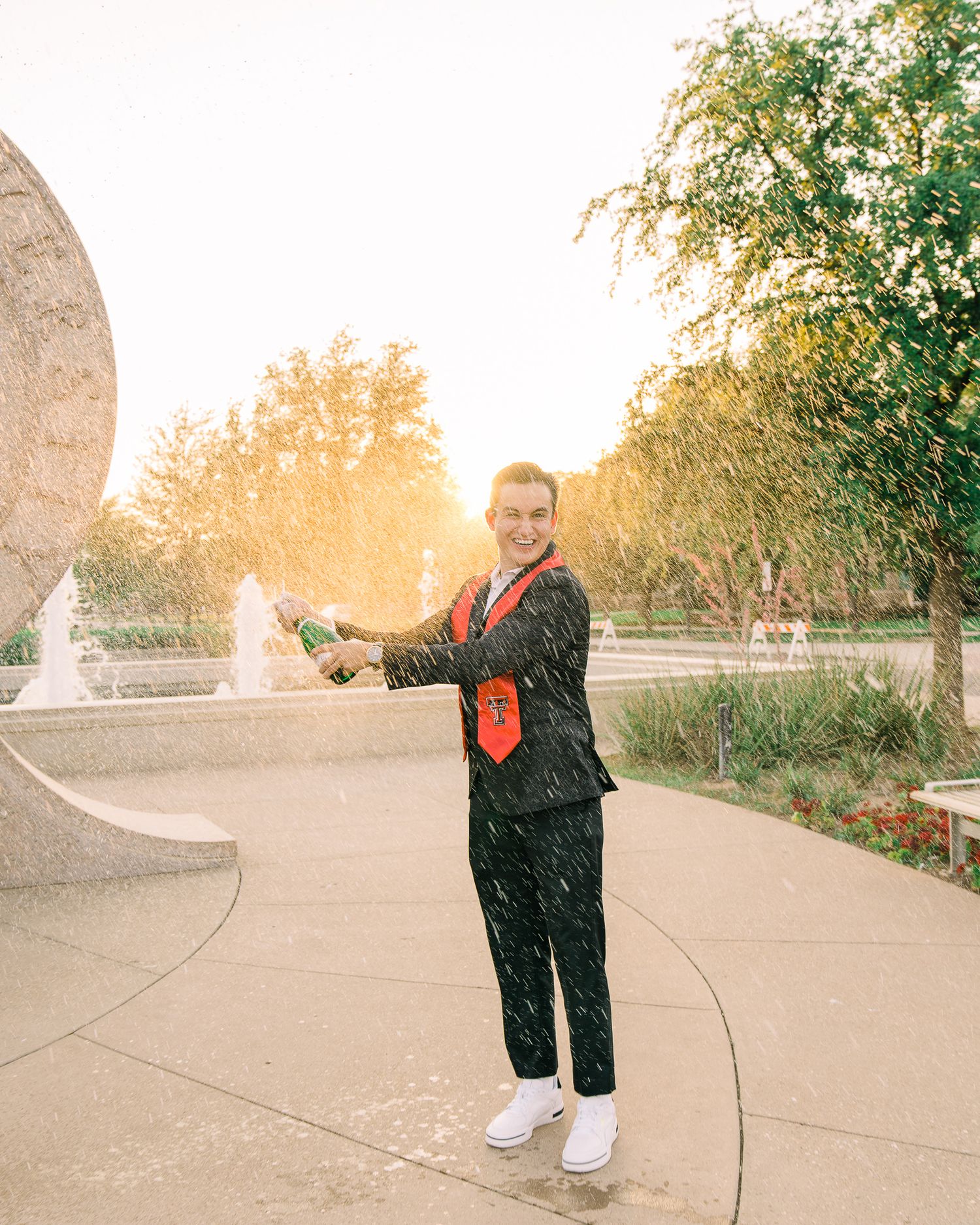 Person in black outfit dancing outdoors on a path during golden hour sunset with trees in background.