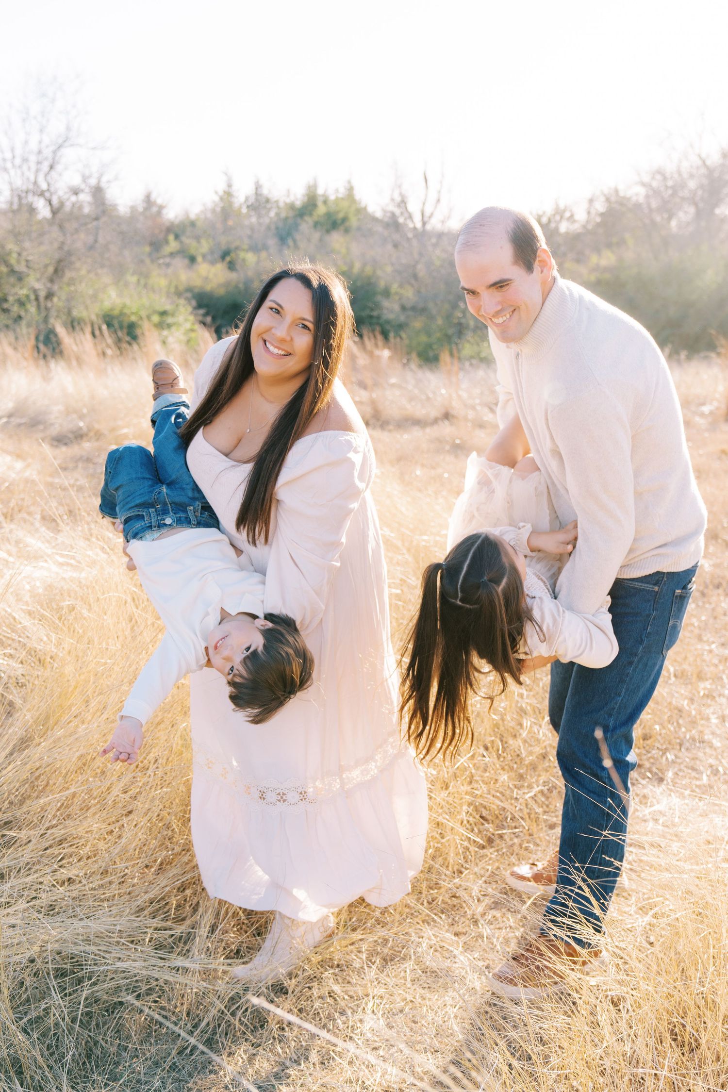 Candid moments of laughter and play in a sunlit meadow with white dress and blue jeans.