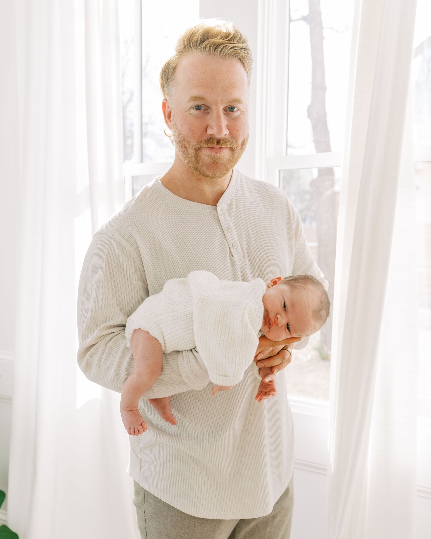 Sweet candid moments of a family bonding with their newborn in a bright white room.