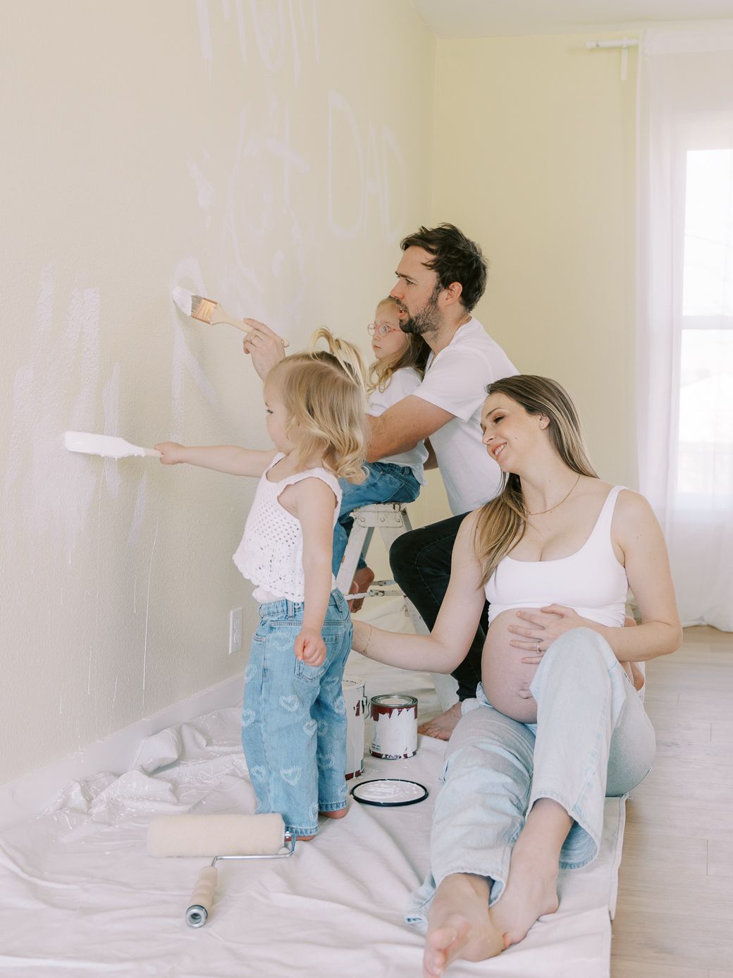 Family working on home improvement project together while sitting on drop cloth.