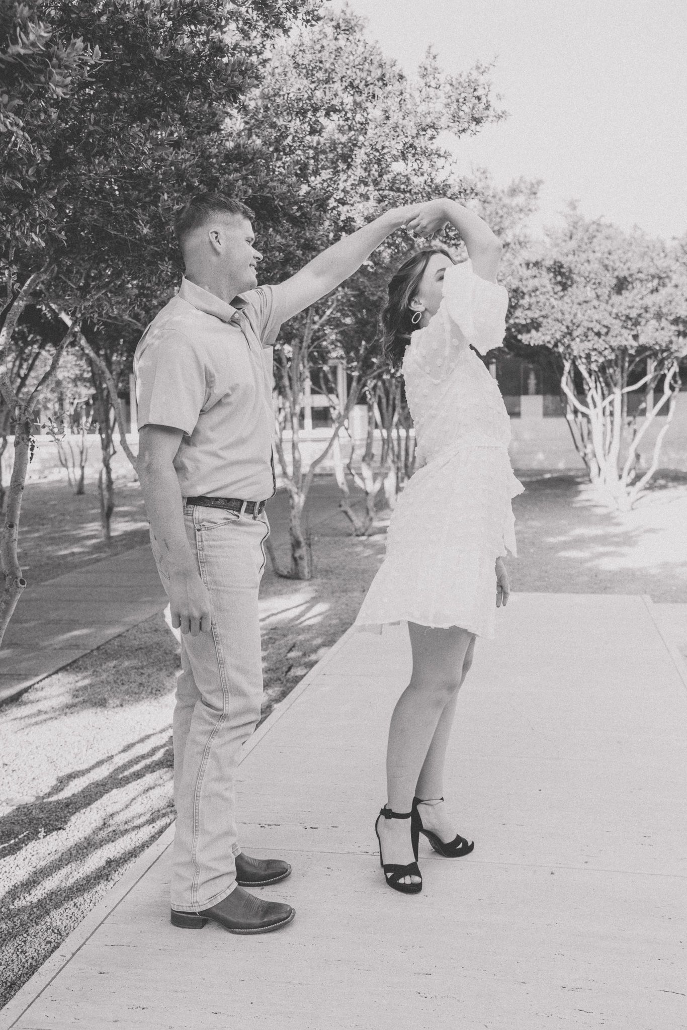 Black and white photos showing playful dance moves on a sunny path between trees.