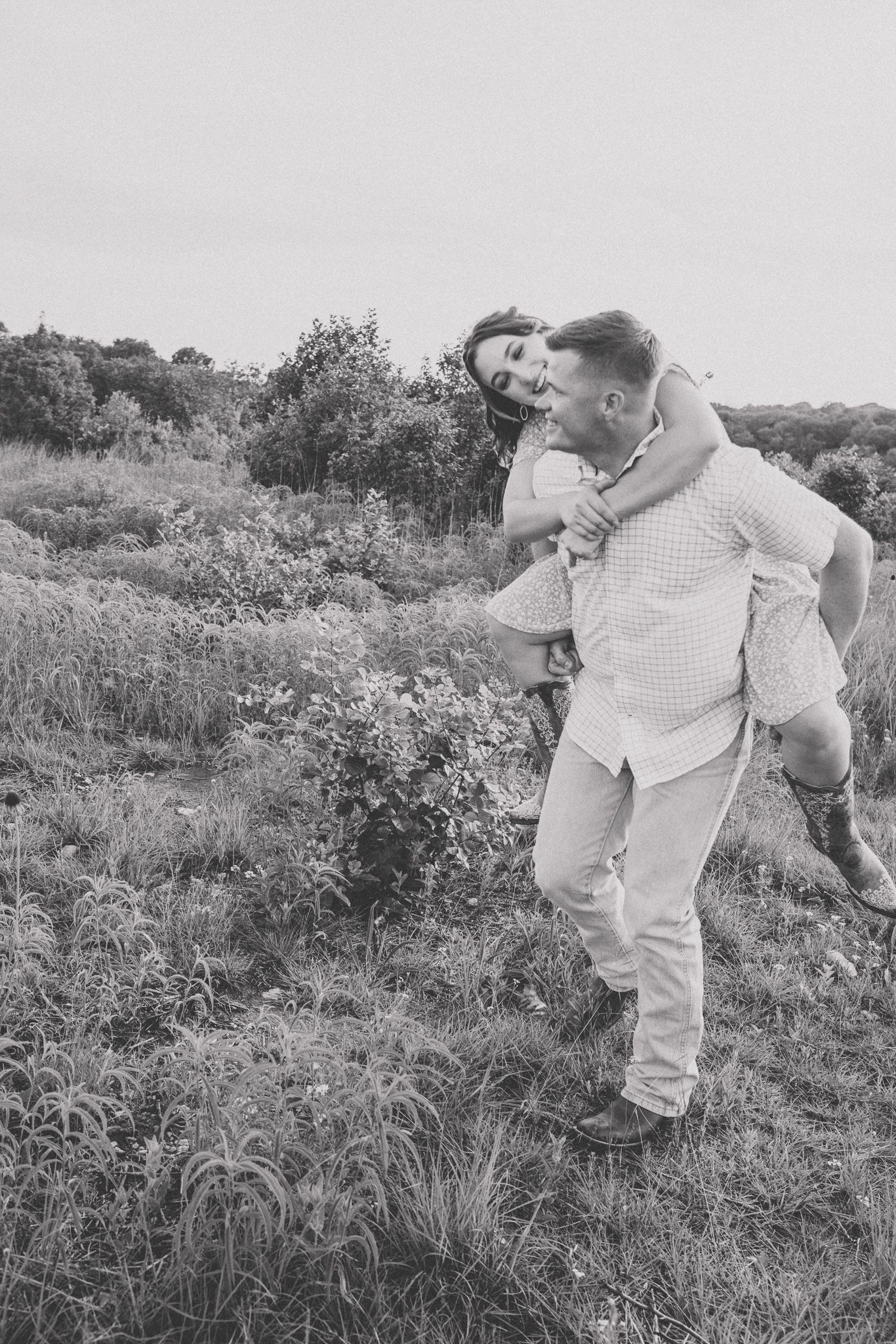 Black and white photo sequence showing playful interaction between two people in a grassy meadow on a sunny day.