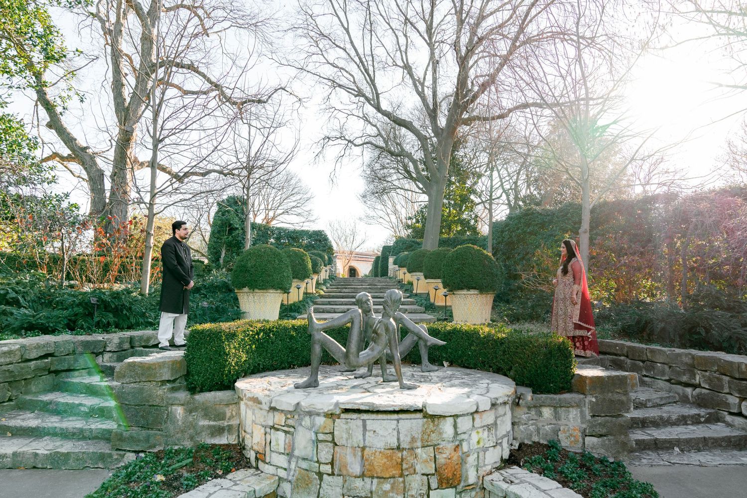 A scenic garden path with manicured hedges and stone walls leading to an elegant venue.