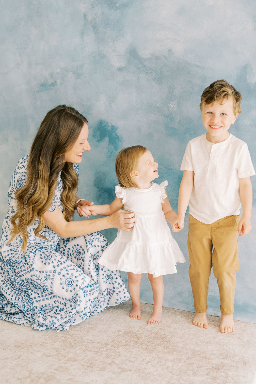 A series of candid family photos against a blue-grey backdrop showing playful interactions and matching white outfits.