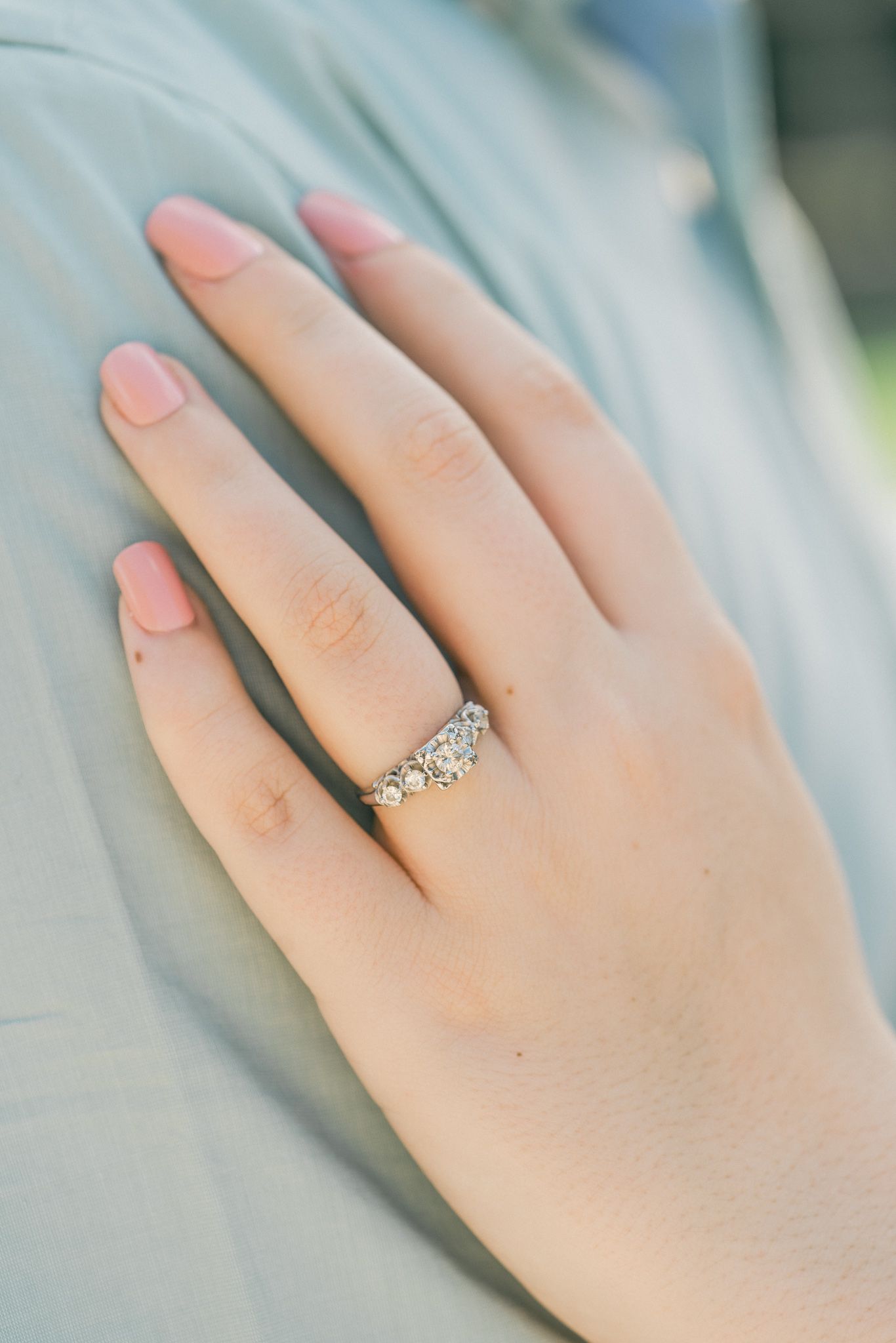 Close-up shots of an elegant engagement ring on a woman's hand against a light blue background.