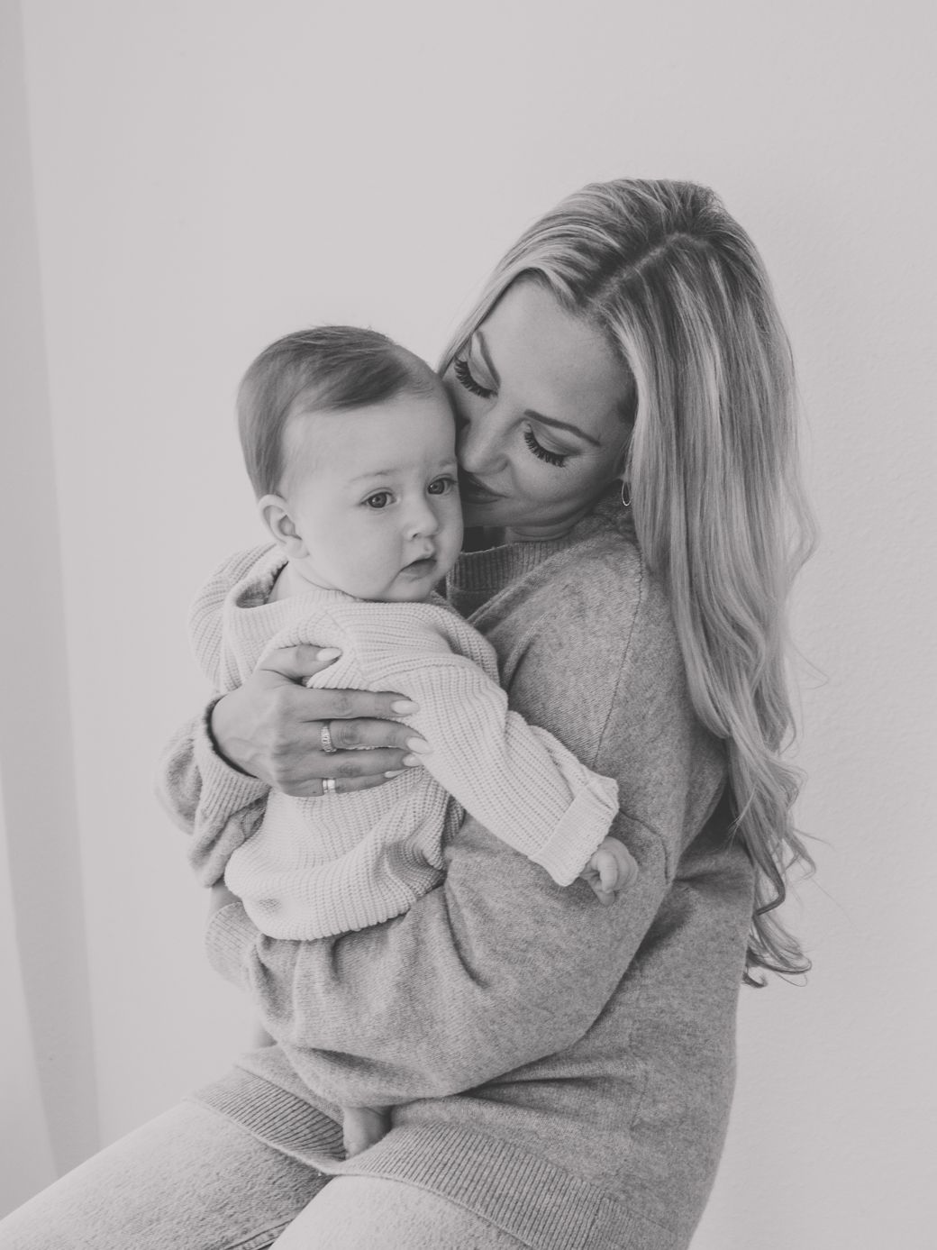 A series of intimate black and white photos showing tender moments between parent and infant in soft lighting.