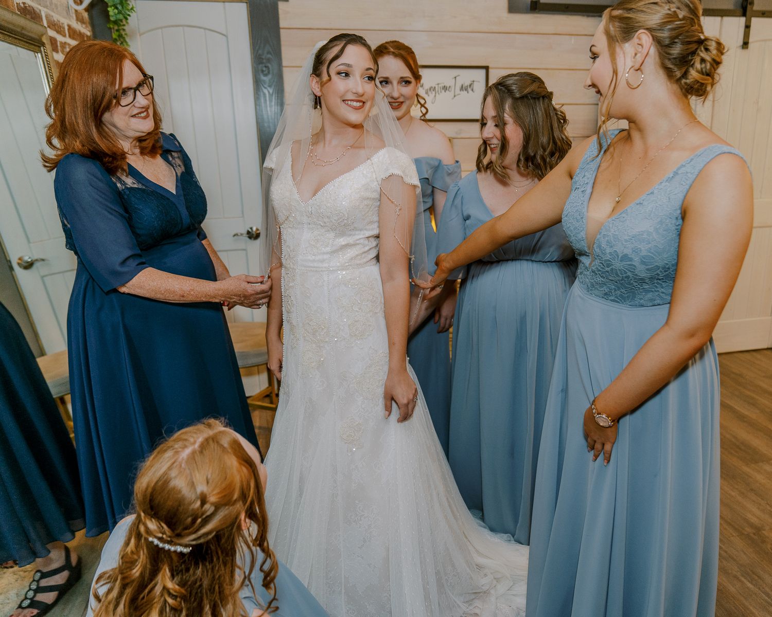 A group in blue bridesmaid dresses and a white wedding gown gather together during a wedding celebration.