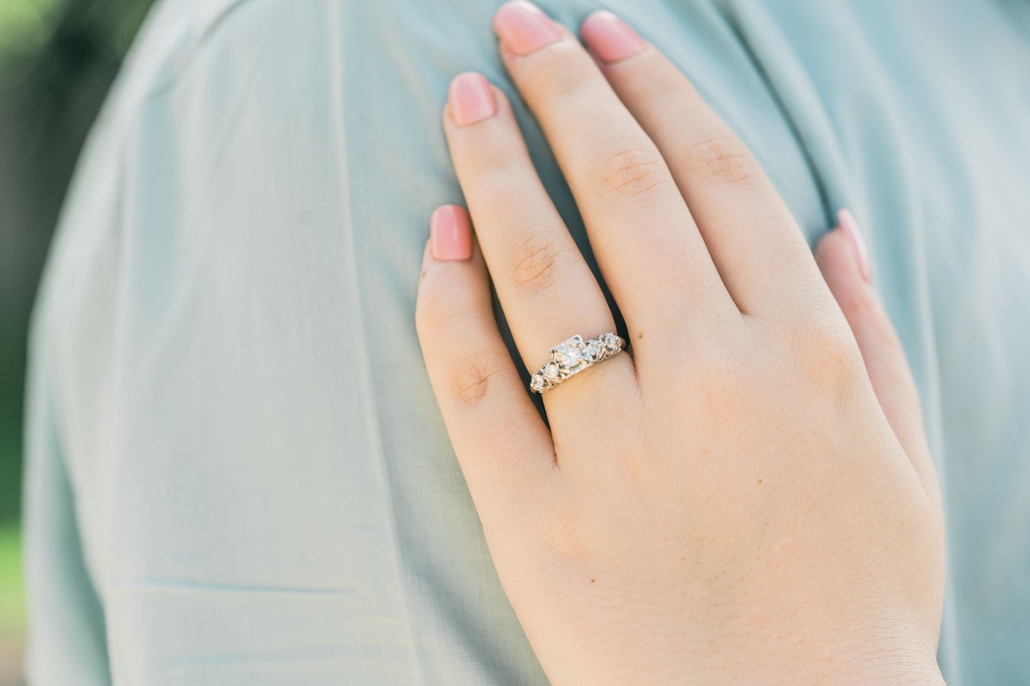 Close up of hands showing off an elegant engagement ring with a sparkling diamond.