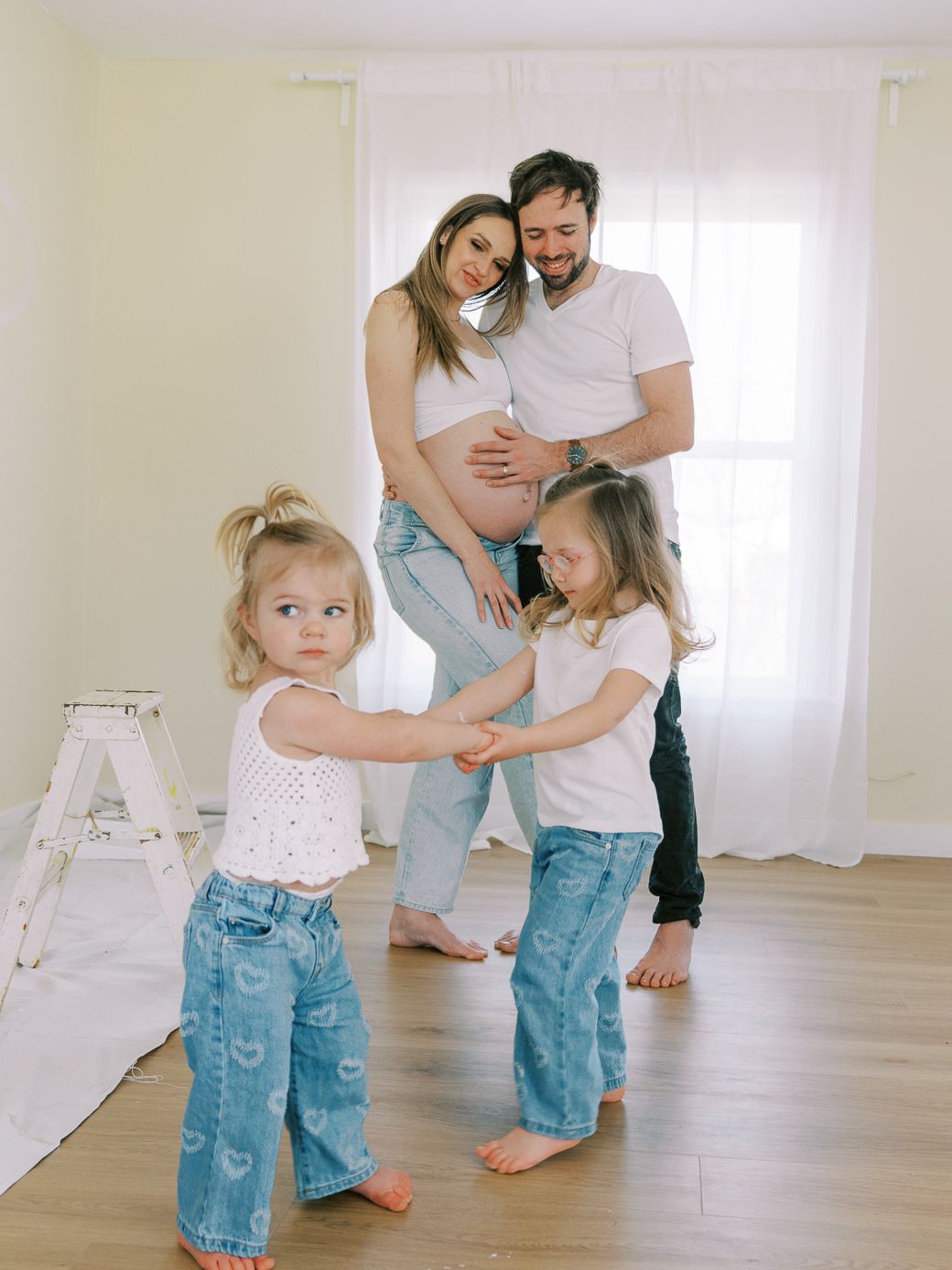 Candid family moments captured while dancing and playing in a minimalist white room.