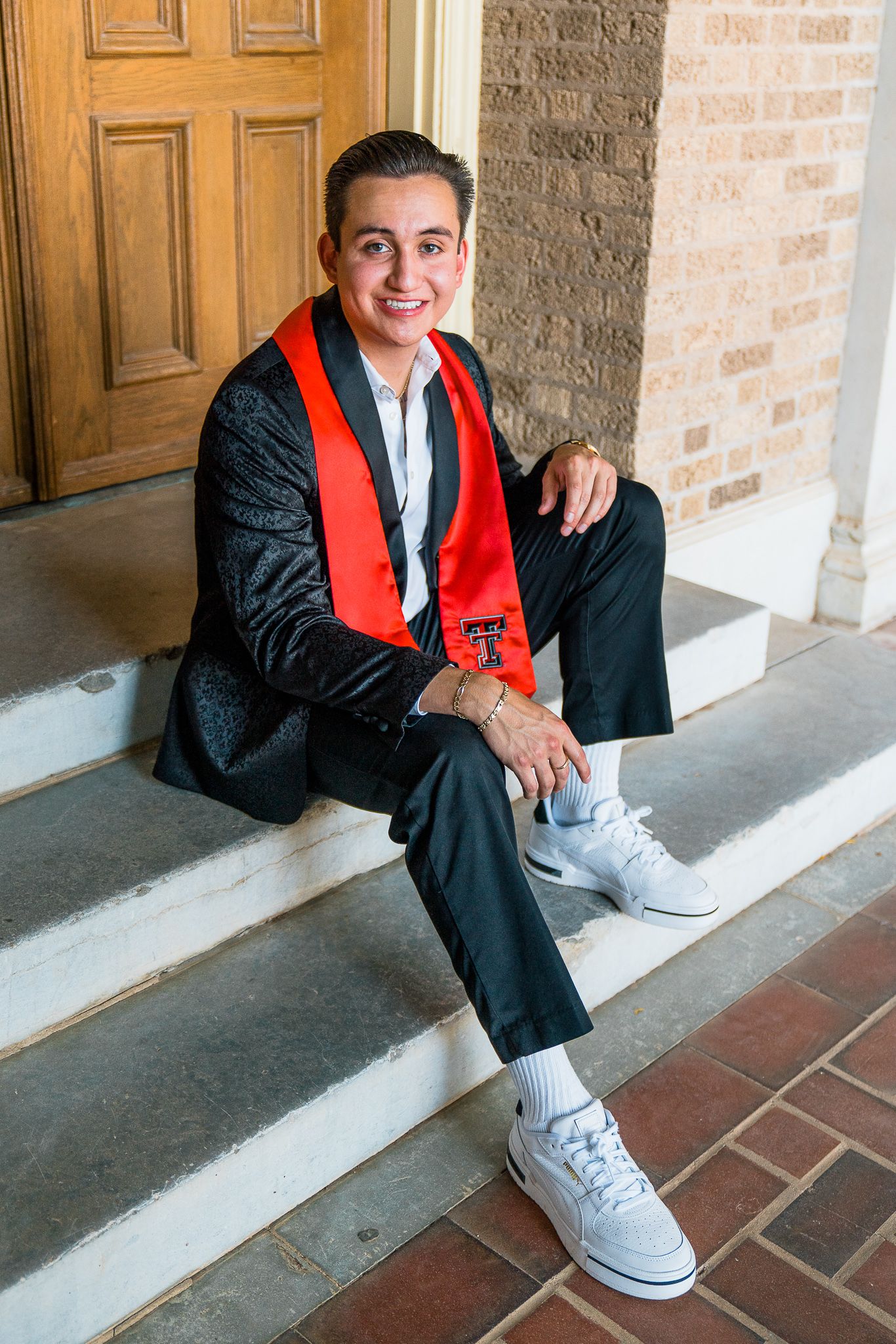 Graduate in cap and gown sits on steps wearing white sneakers in a series of casual portrait photos.