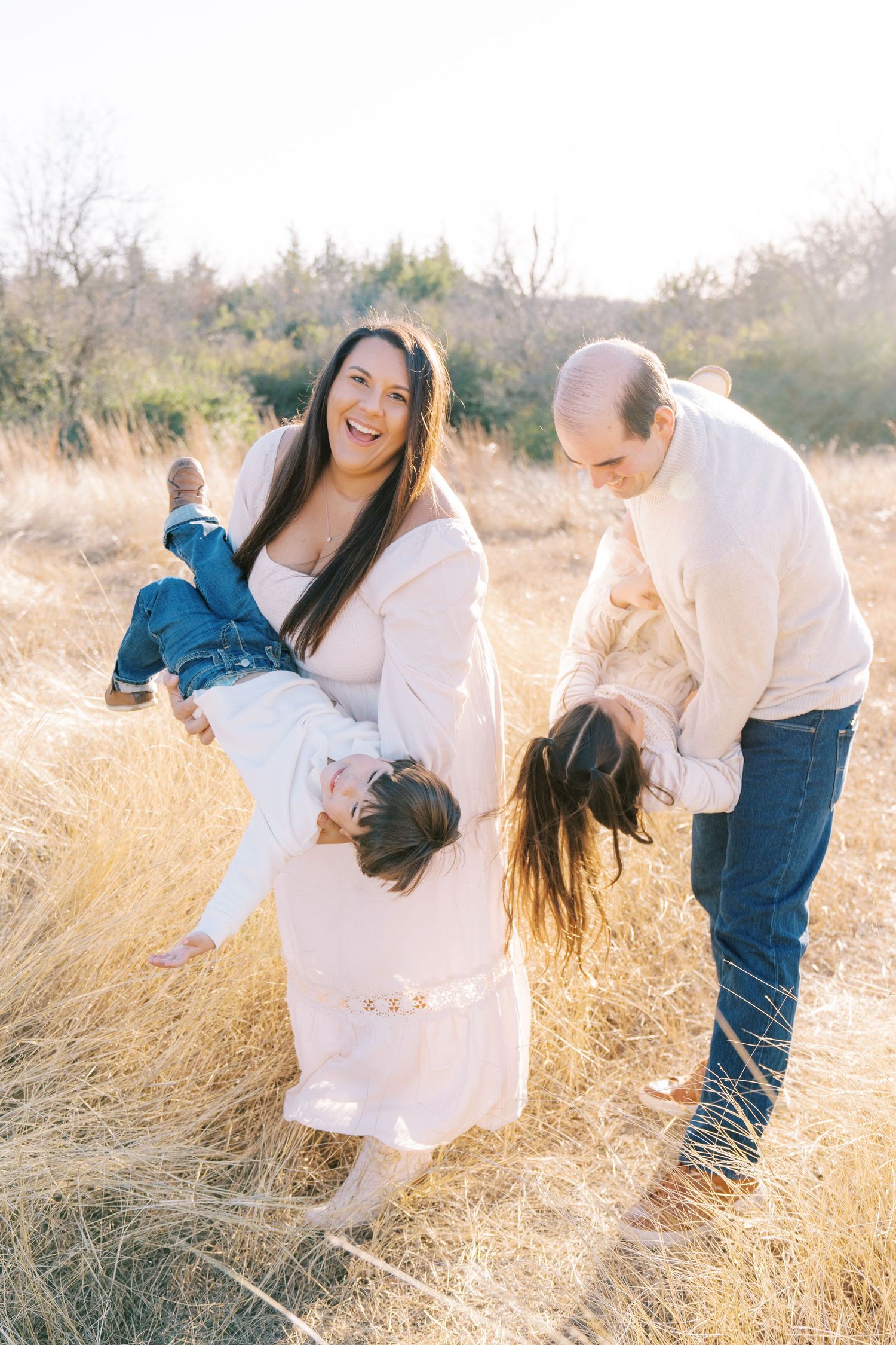 Joyful interaction between two people in a sun-drenched field of tall grass during golden hour.