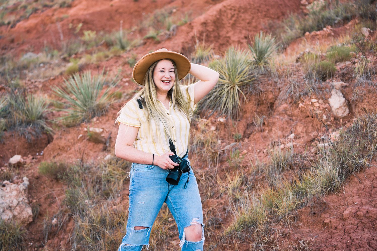 A person in blue jeans and pink top explores the vibrant red rock formations in a desert landscape.